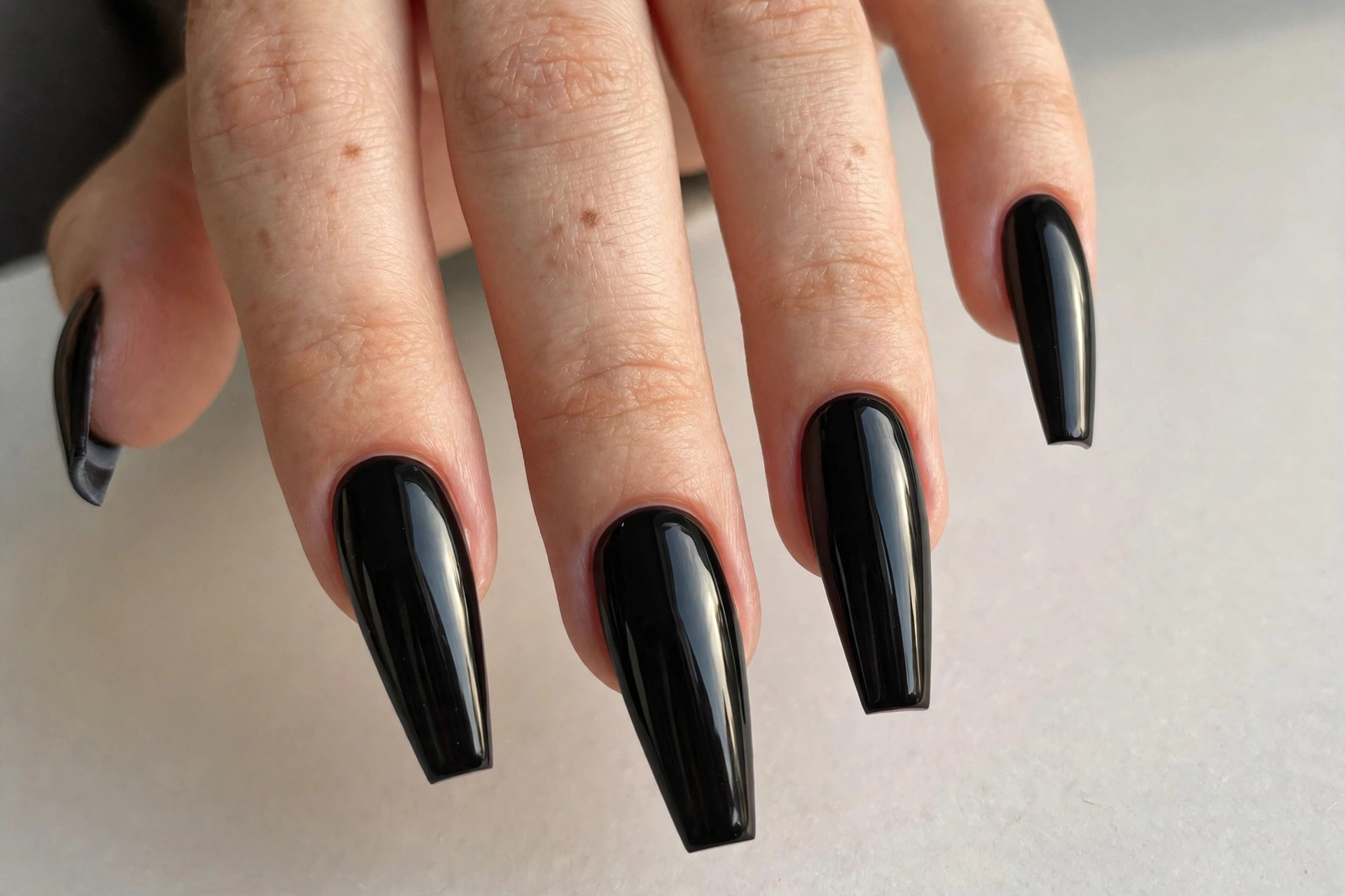 Long glossy black manicure on dramatic coffin stiletto shaped nails