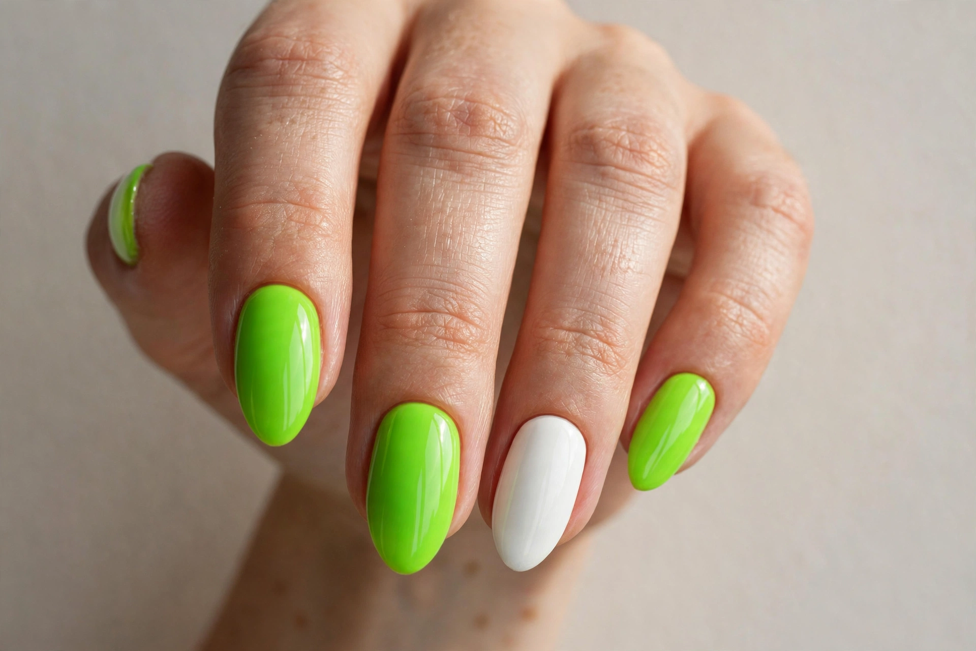 Close-up of bright lime green neon manicure with a white accent nail on almond shaped nails