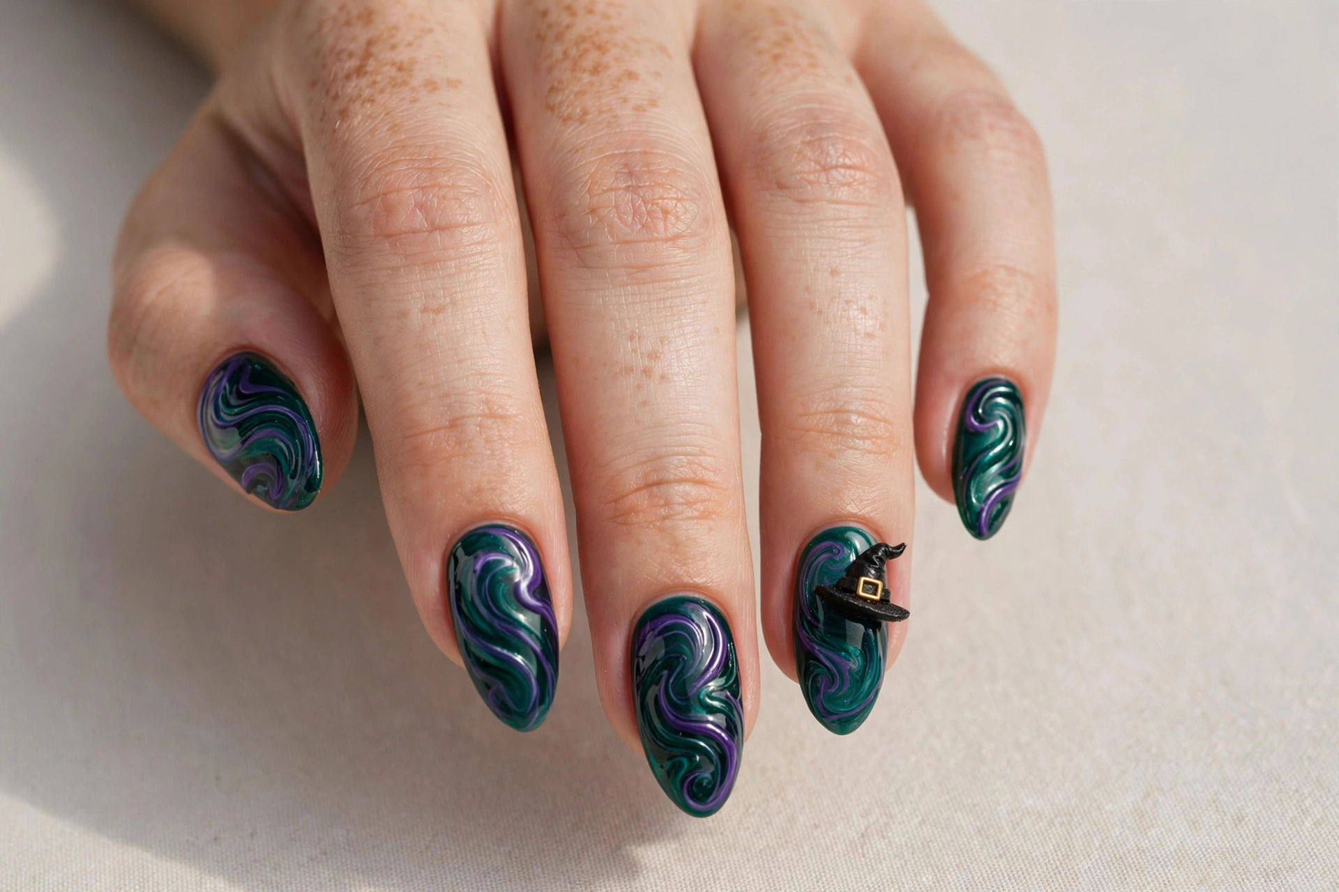 Deep green and purple swirled nail art with witch hat accent