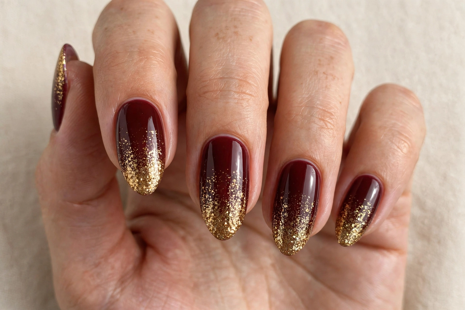 Almond nails with burgundy and gold glitter ombre manicure