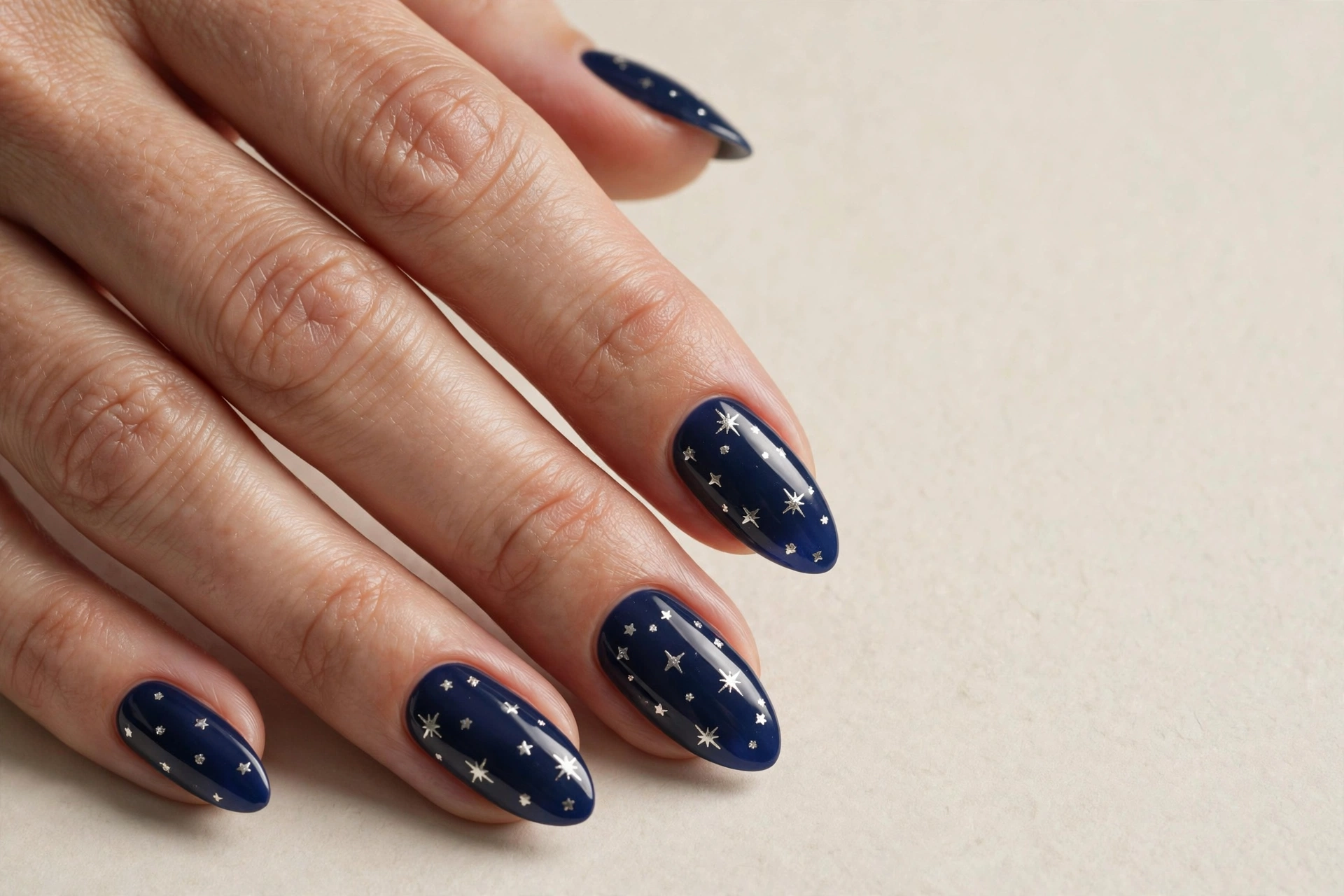 Deep navy blue almond nails with tiny silver stars
