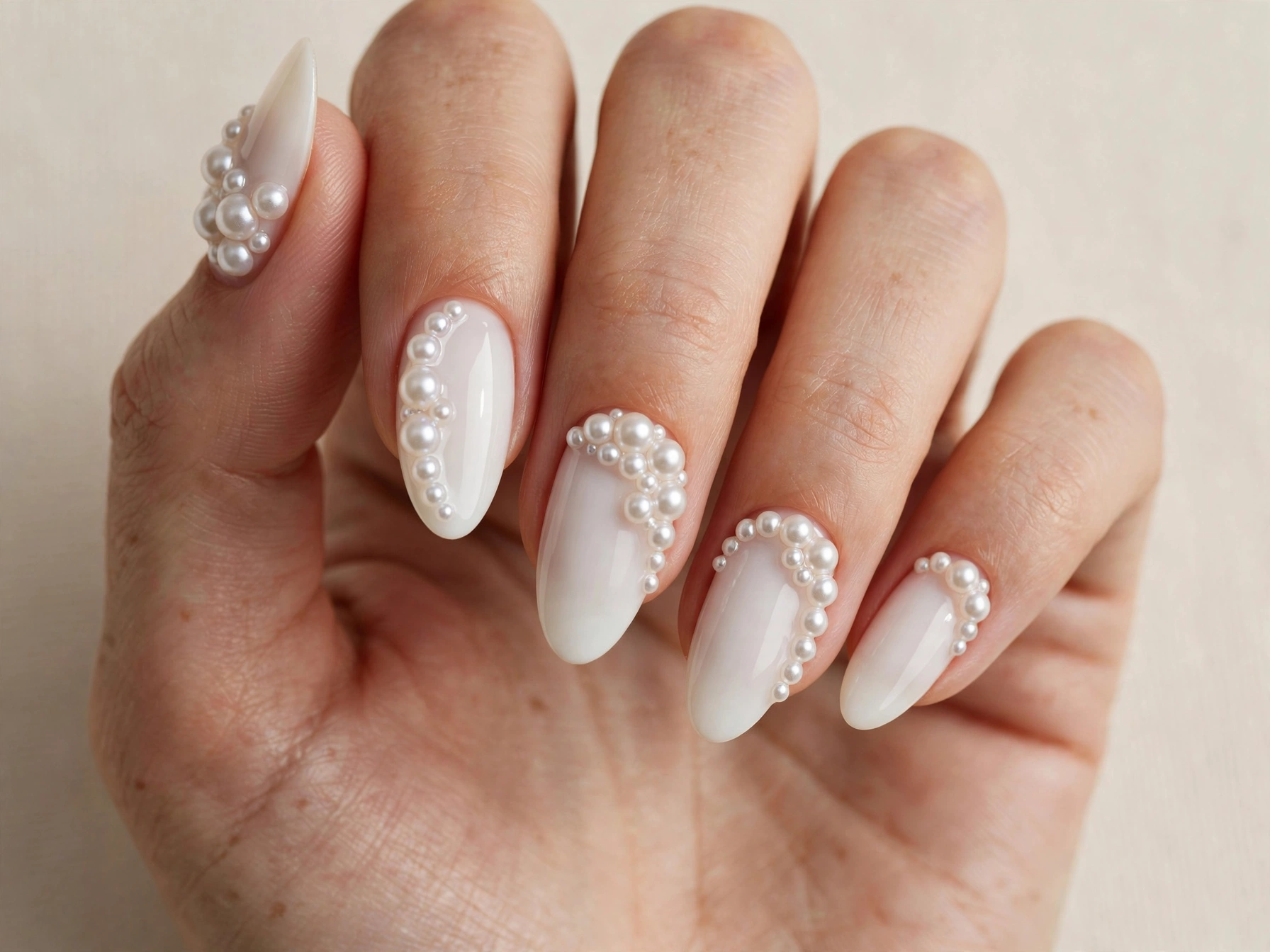 Elegant pearl 3D embellishment nail art on a milky white base