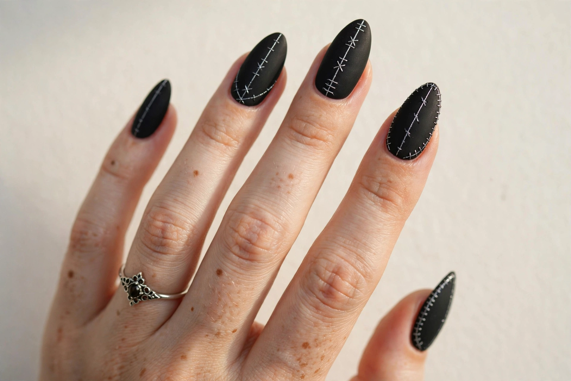 Matte black nails with thin silver stitch lines