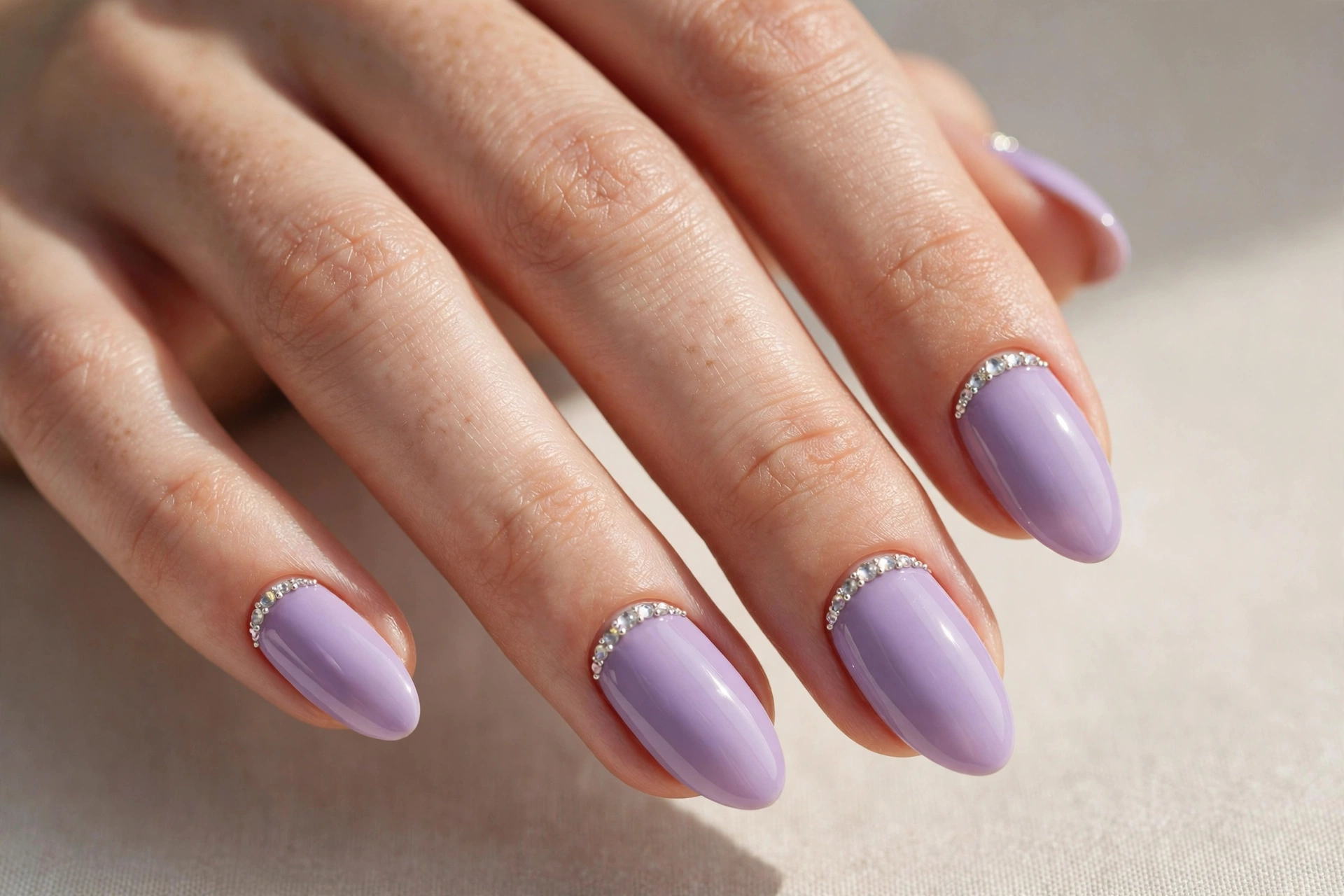 Lavender nails decorated with small sparkling rhinestone crystals along the cuticle