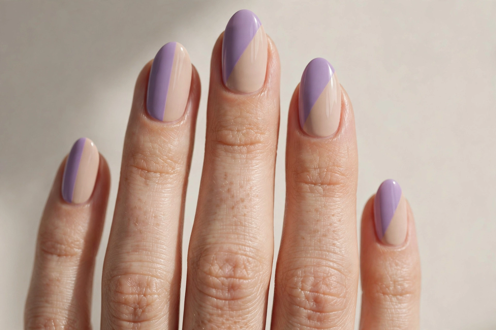 Color block manicure with half lavender and half nude beige split diagonally