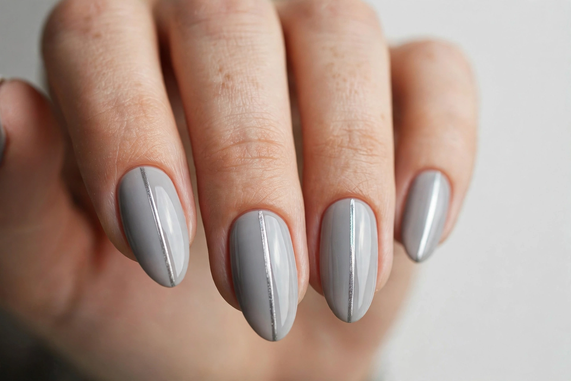 Metallic silver lines on soft grey nails