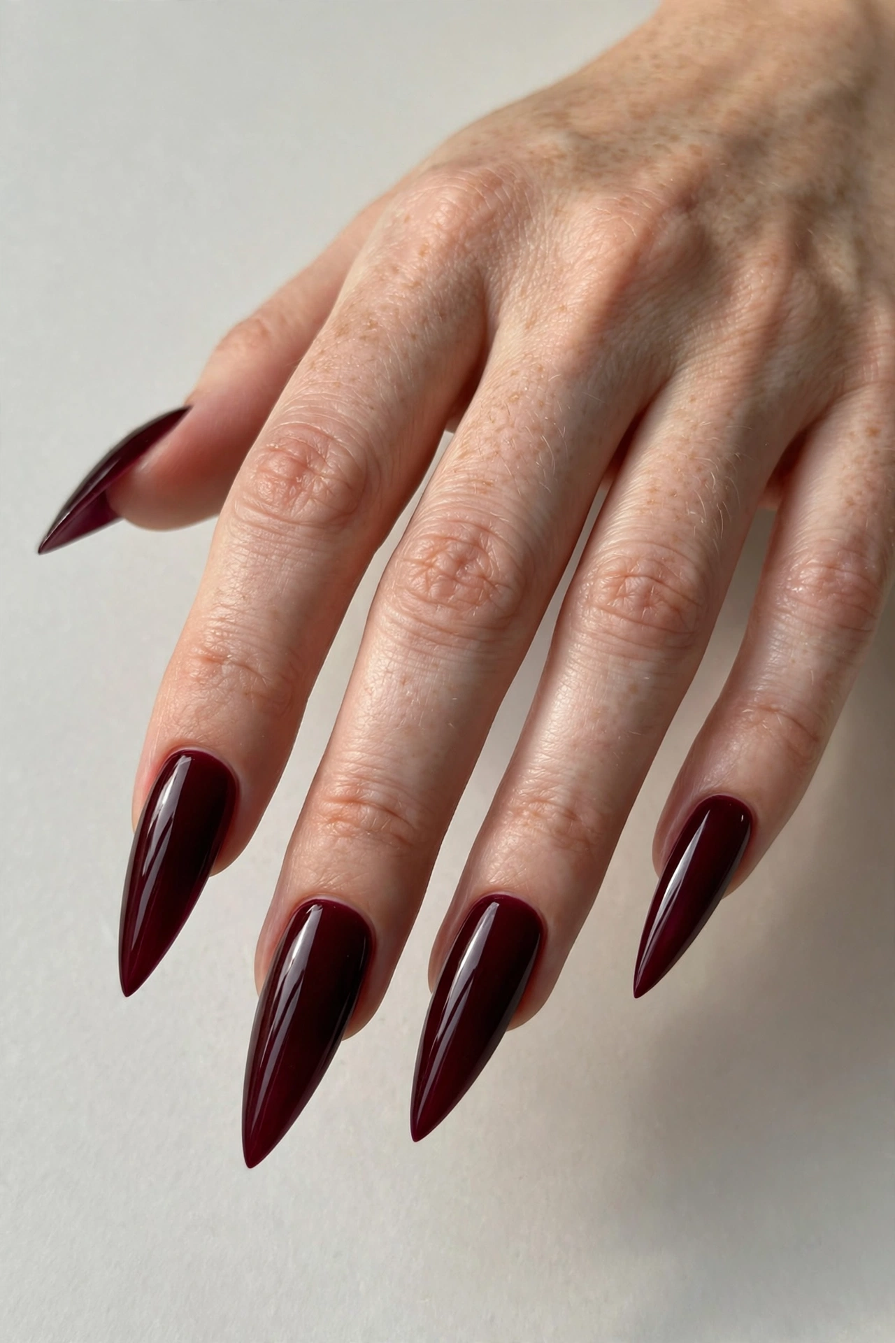 Burgundy wine glossy manicure on long stiletto shaped nails