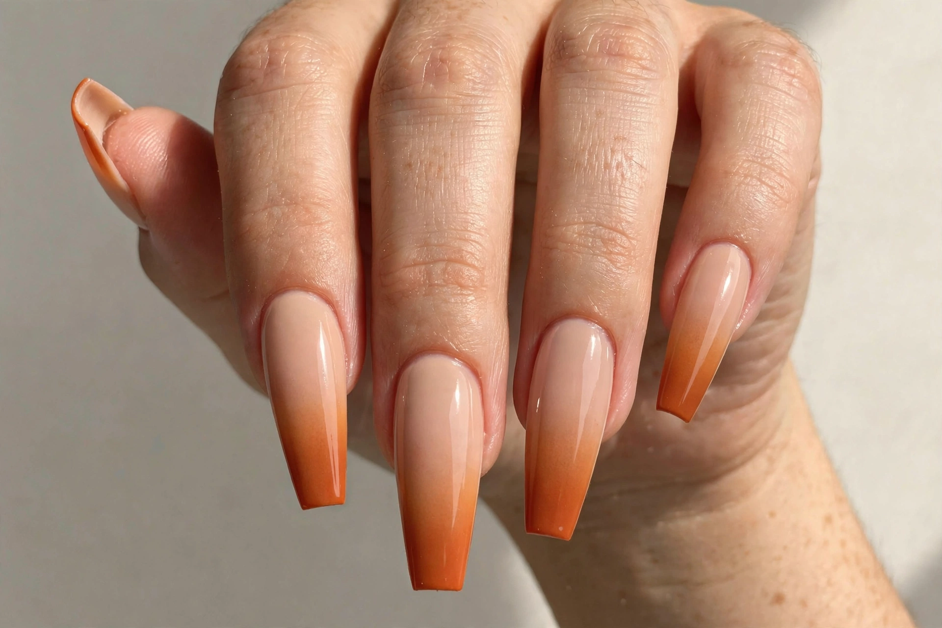 Pumpkin spice orange to nude ombre gradient manicure on long coffin nails