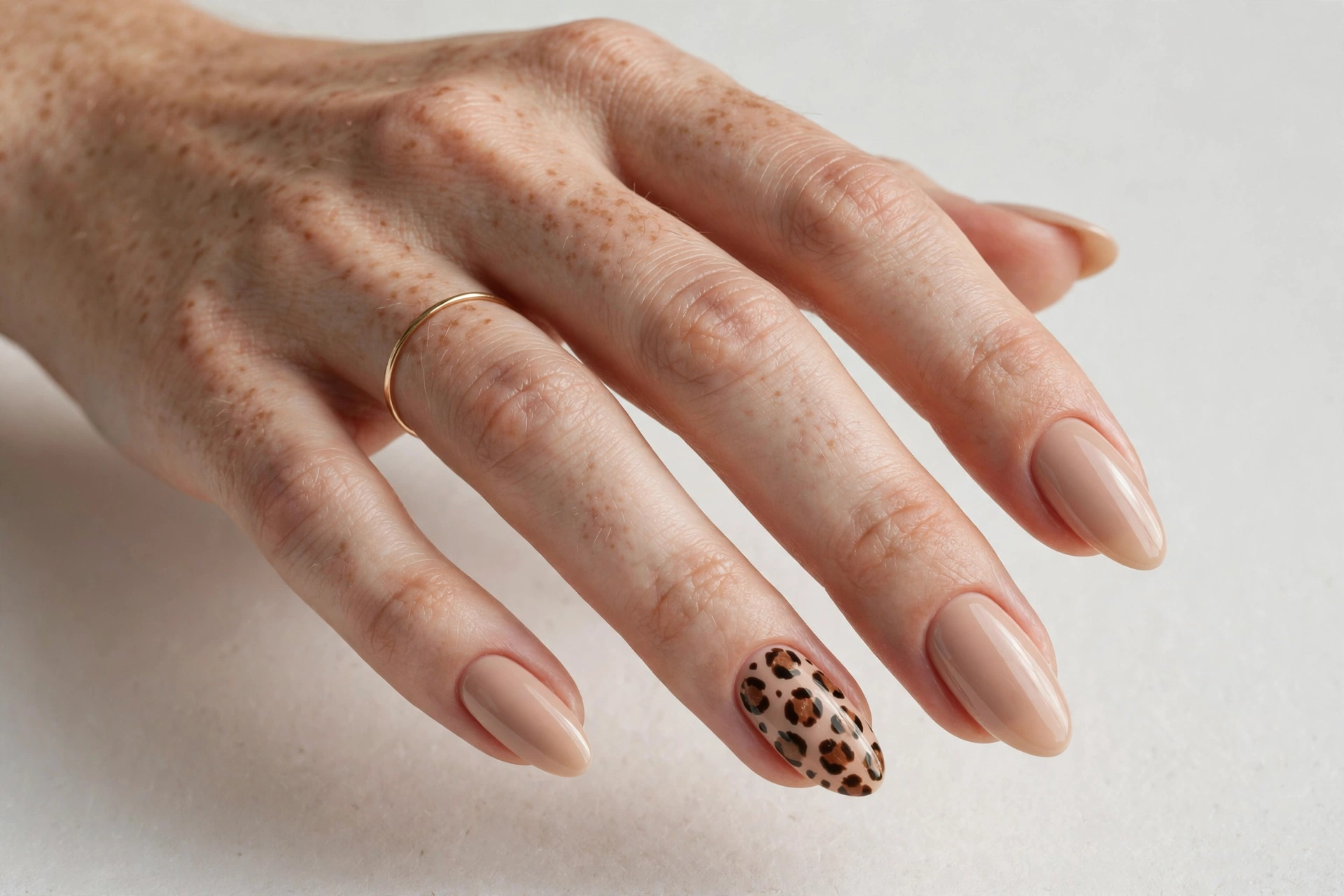 Leopard print accent nails on nude base, almond-shaped nails