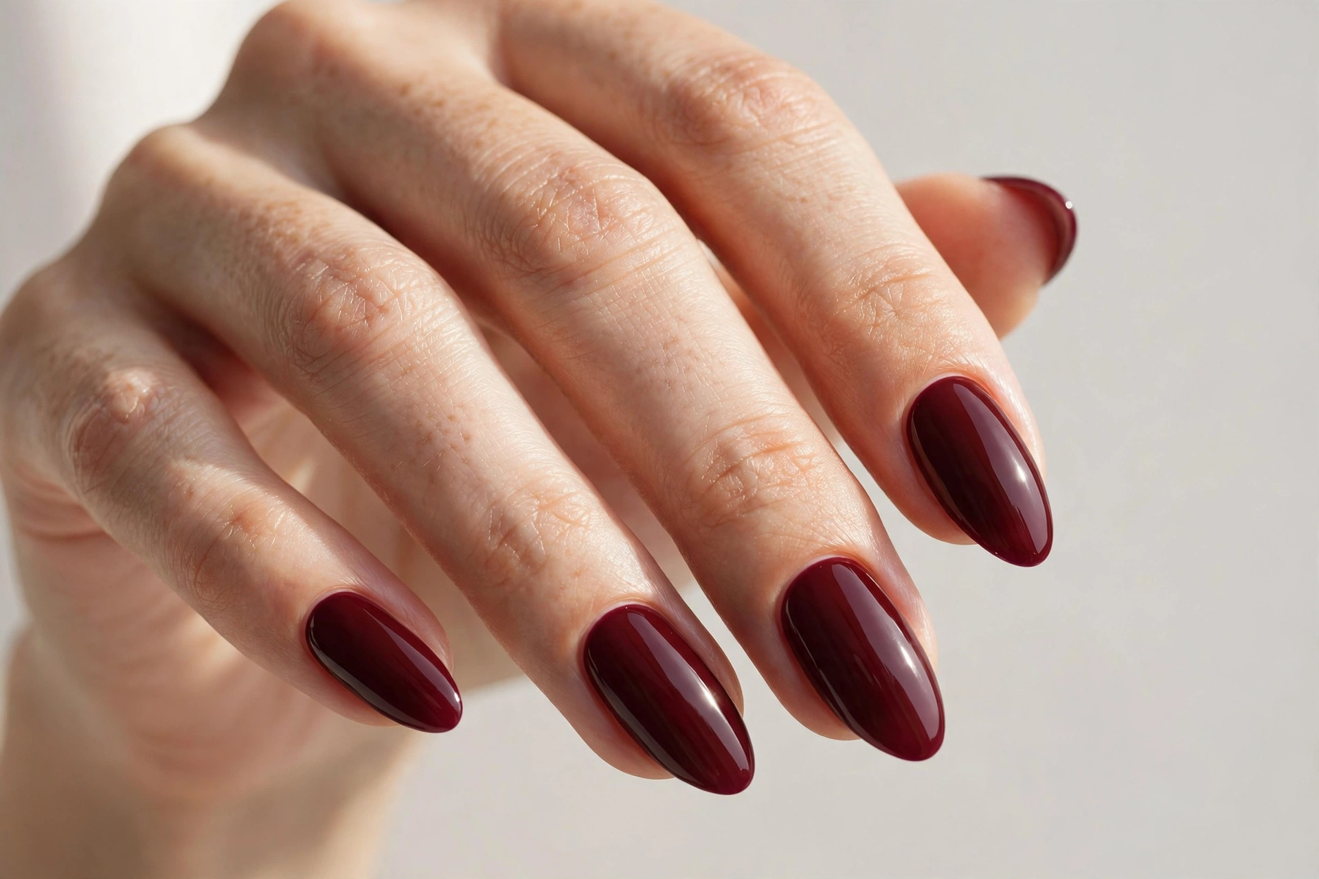 Deep burgundy glossy manicure on almond nails