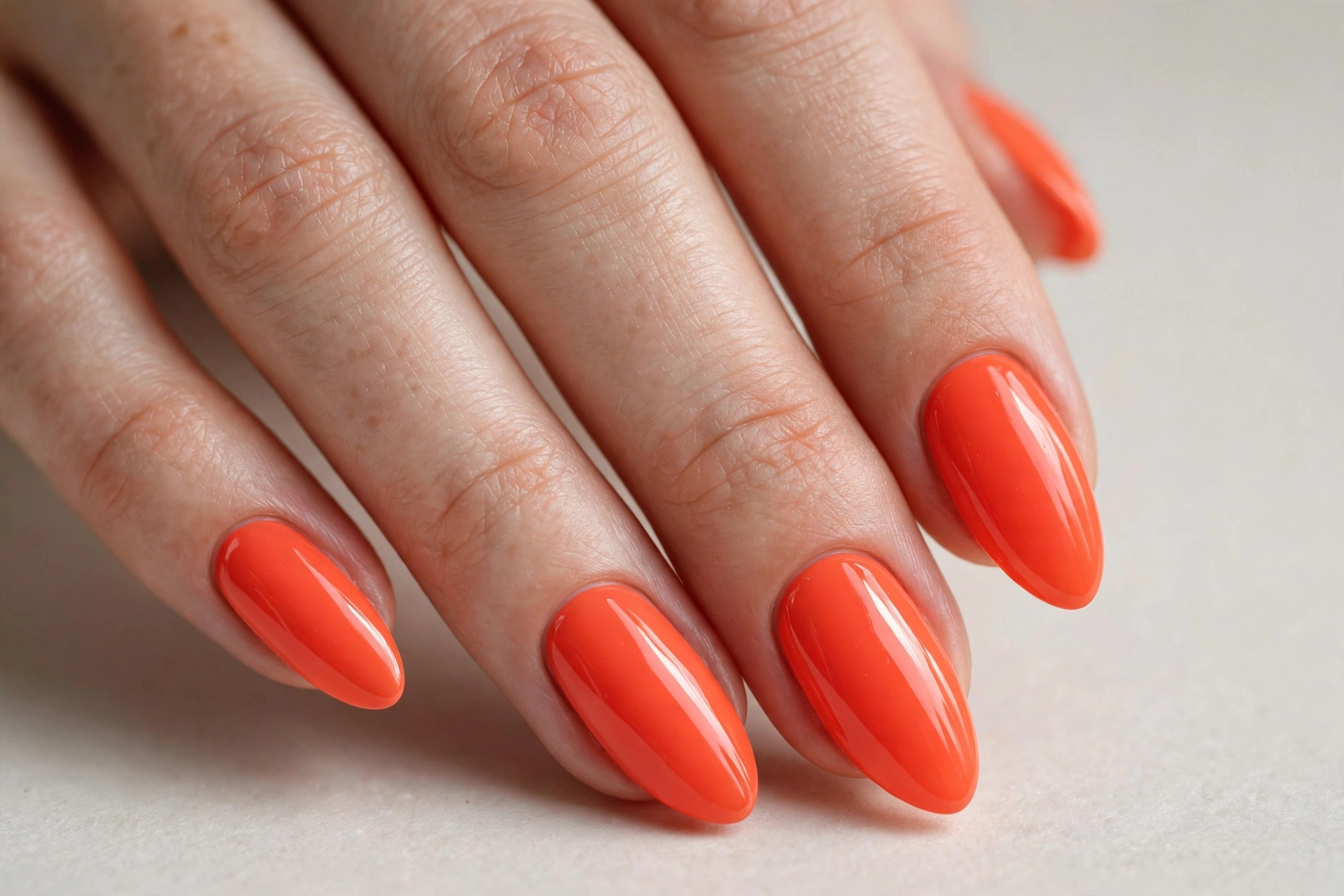 Bright coral orange nail varnish manicure on almond shaped nails