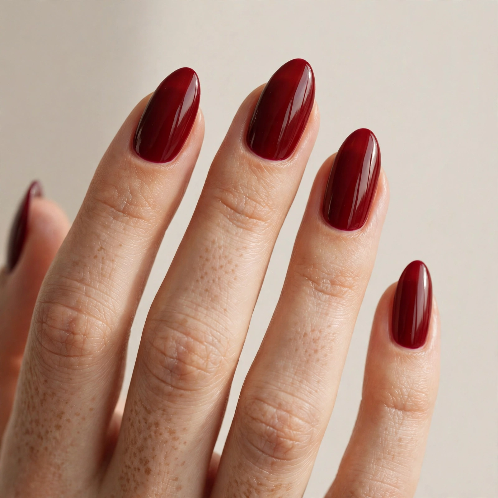 Close-up of a woman's hand with deep red glossy nails