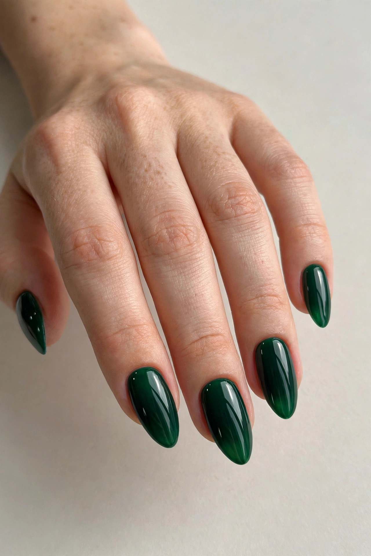 Rich emerald green glossy nails in a deep jewel tone