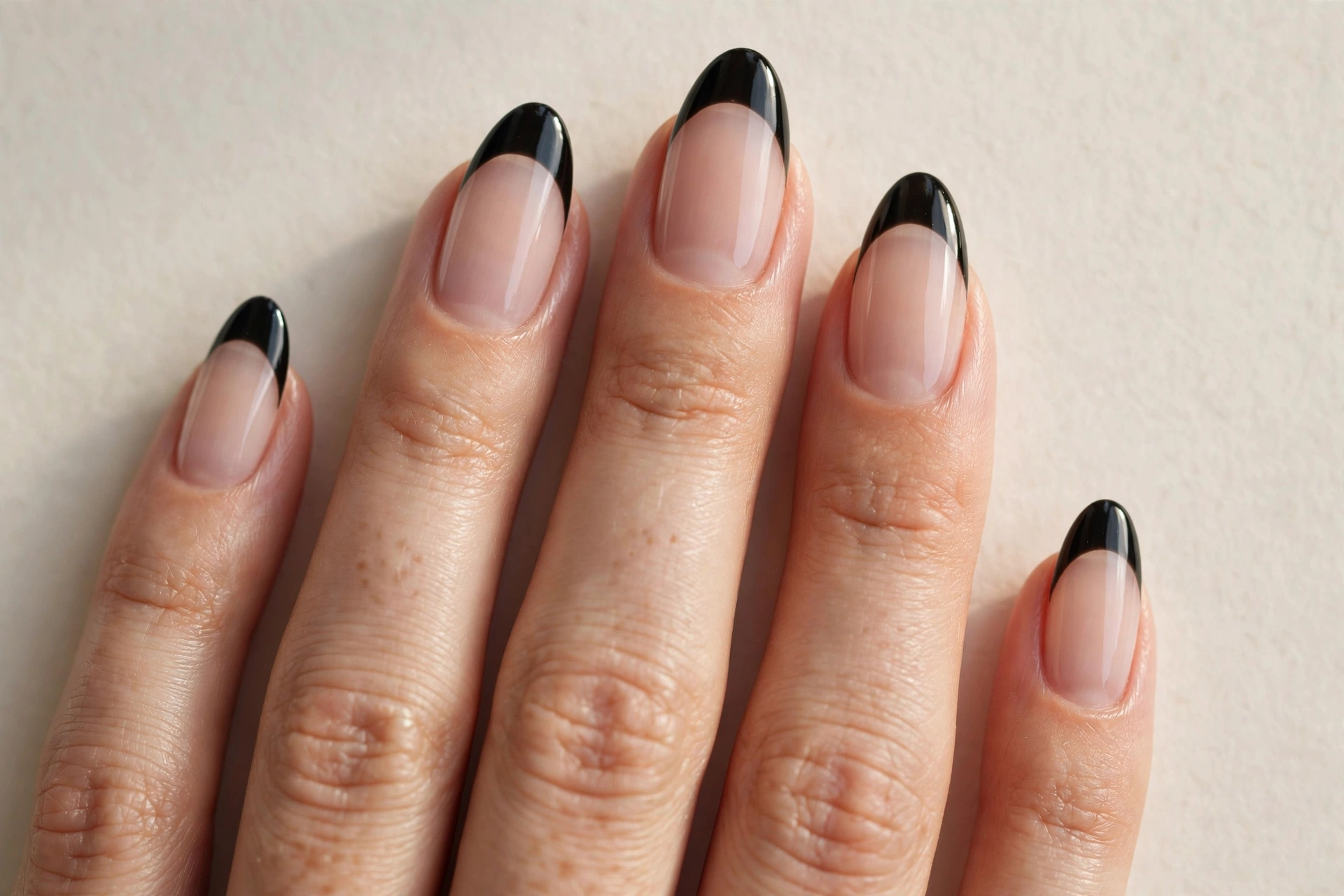 Black French tip manicure with glossy tips on a sheer nude base