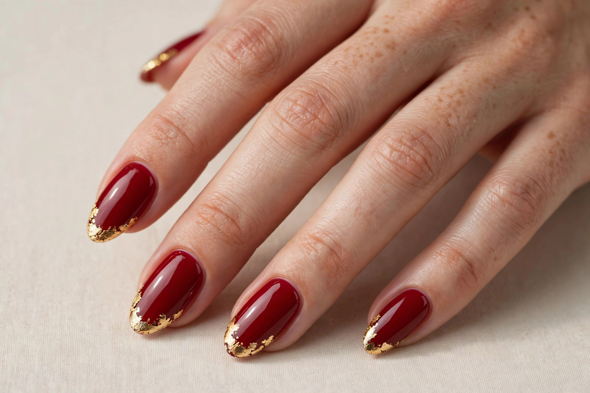 Glossy red Christmas nails with gold foil tips