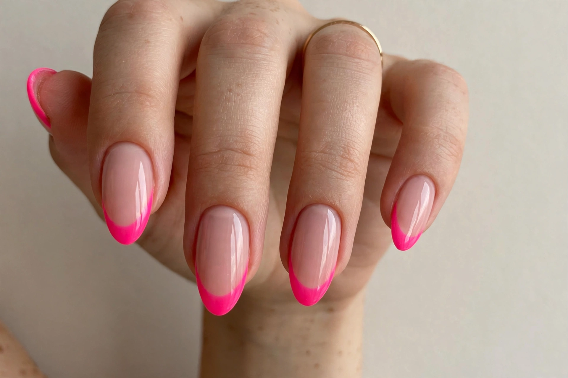Hot pink neon French tip nails on a nude base