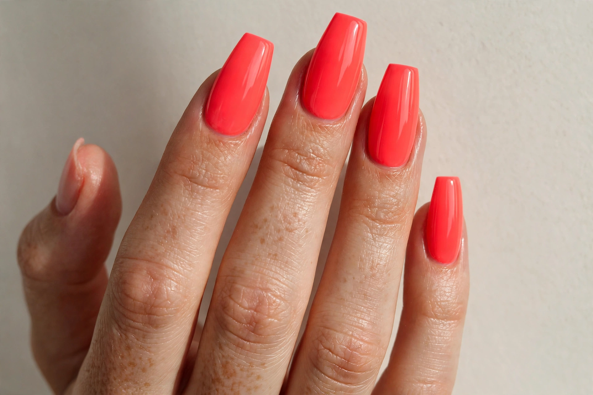 Neon coral solid nails on a long coffin shape