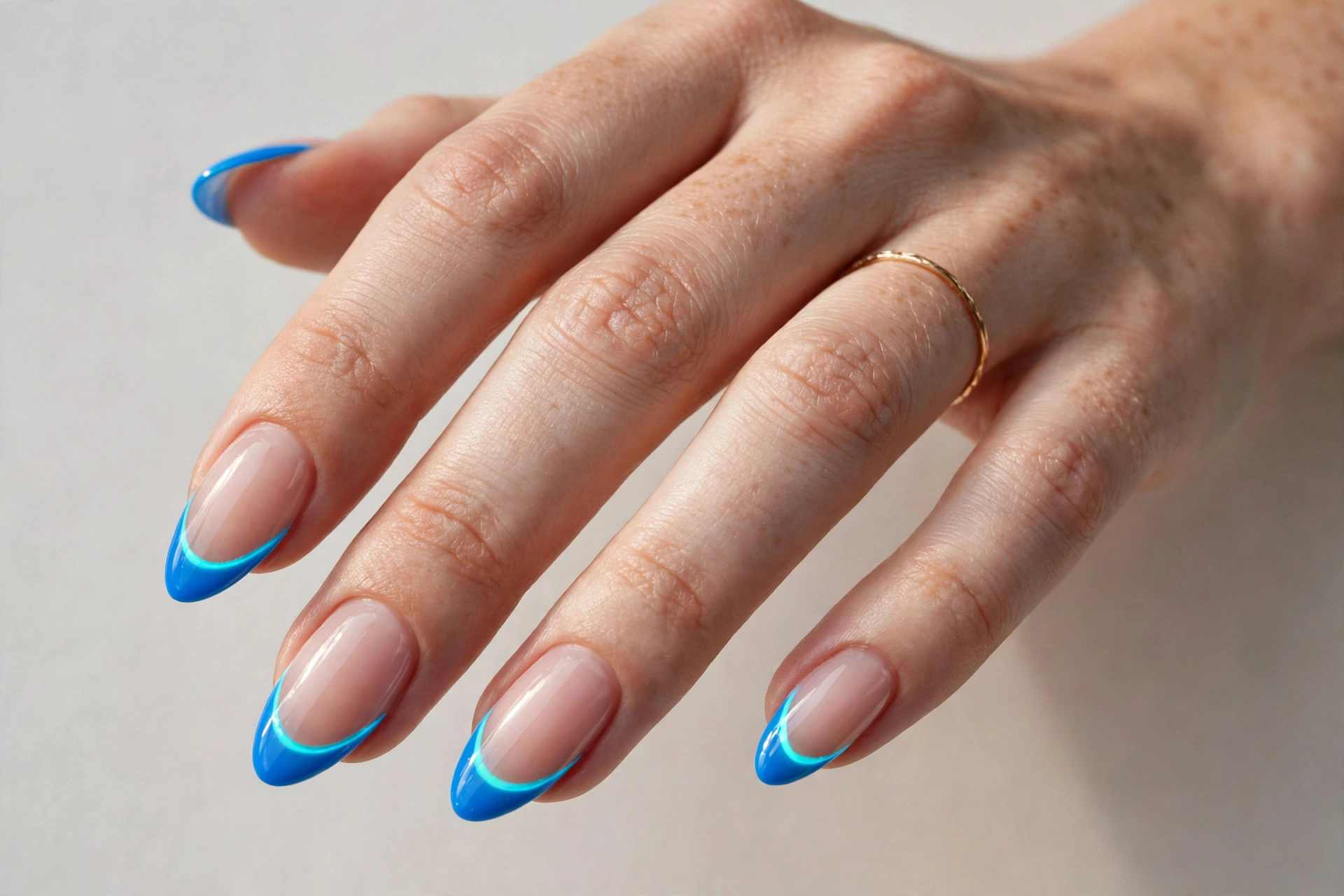 Electric blue French tip nails with a glowing neon inner outline