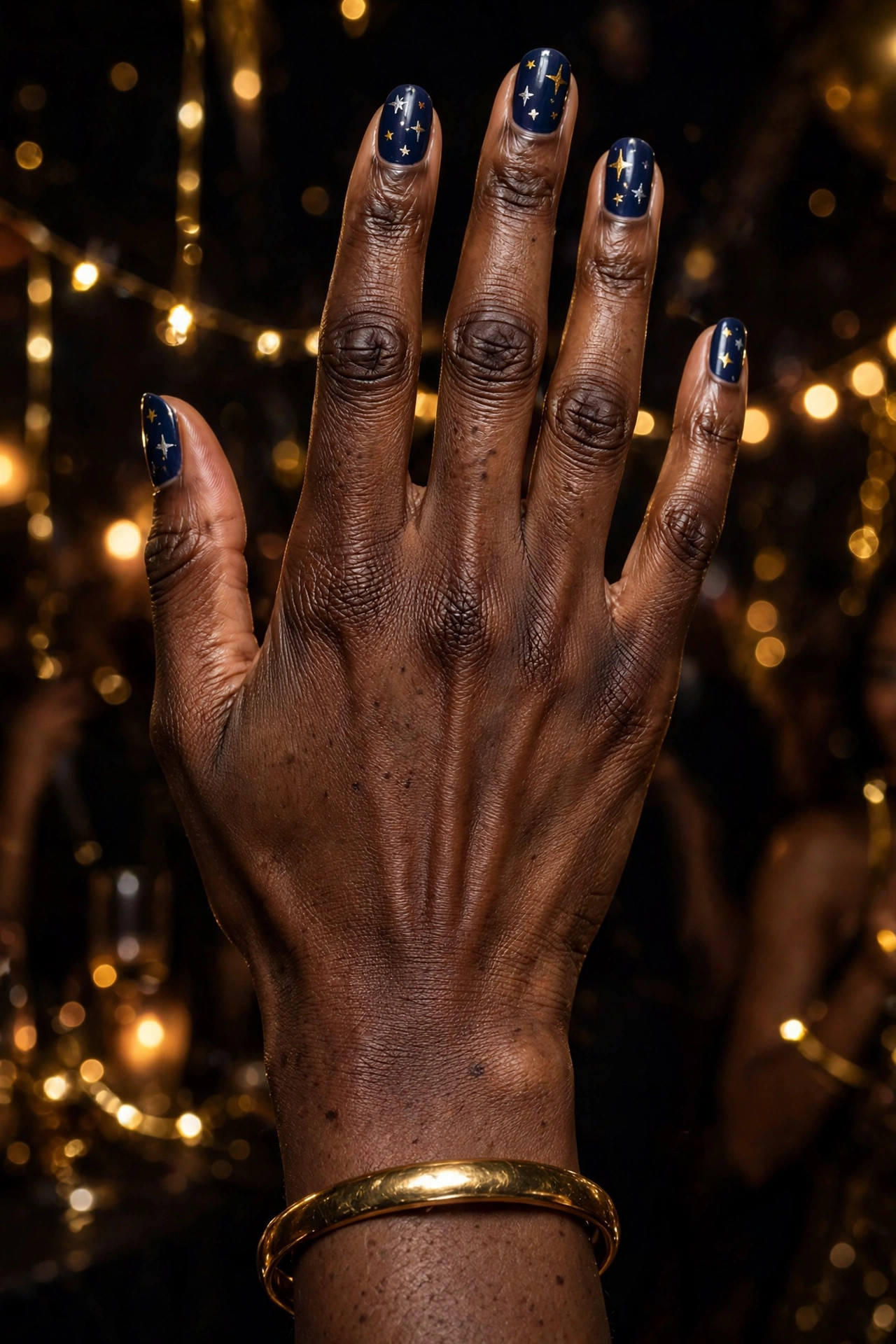 Deep navy New Year's nails with tiny gold and silver hand-painted stars on almond nails