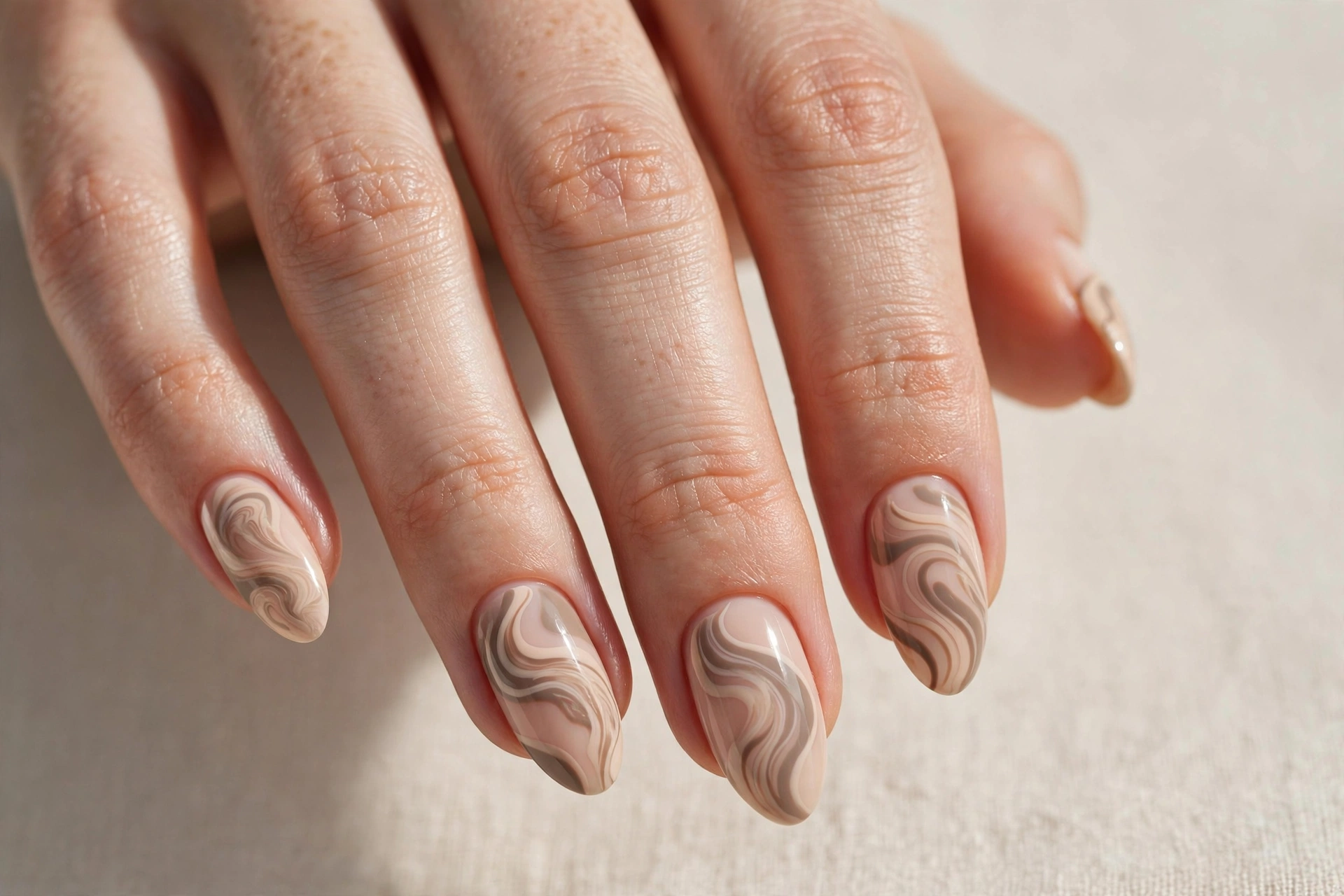 Nude manicure with abstract beige and taupe swirls