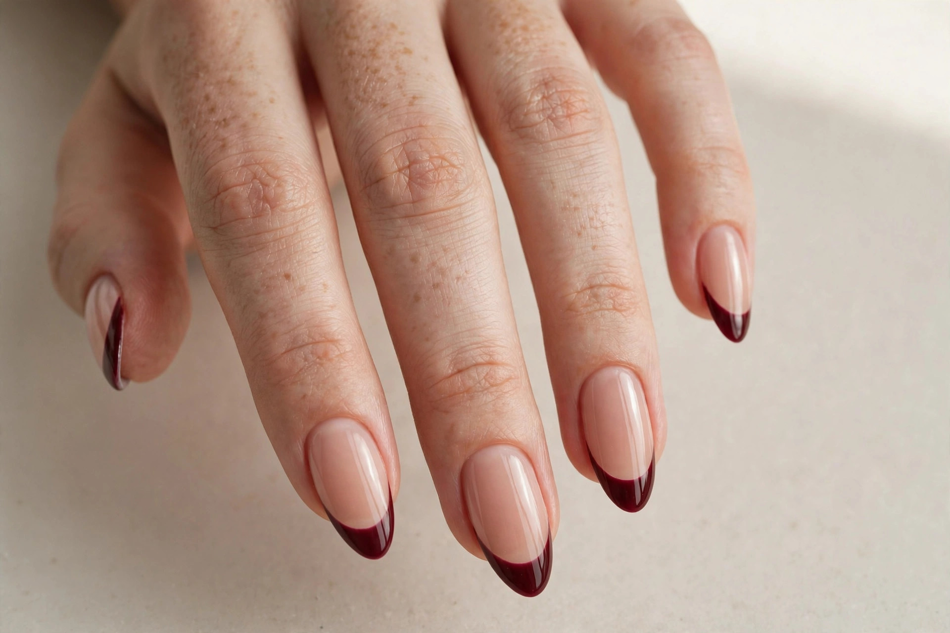Deep burgundy french tips on nude almond nails