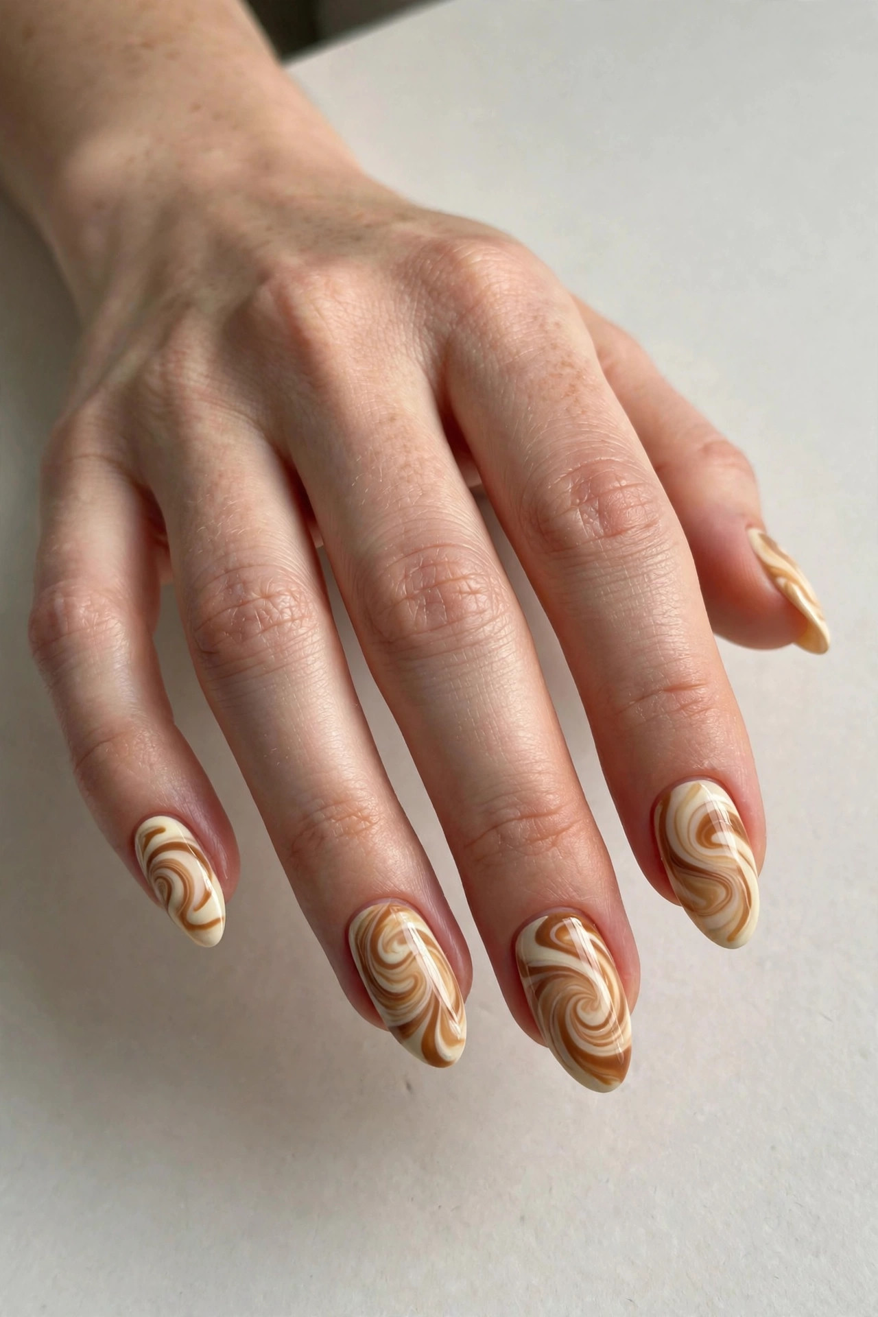 Caramel latte swirl nail art in cream and caramel tones