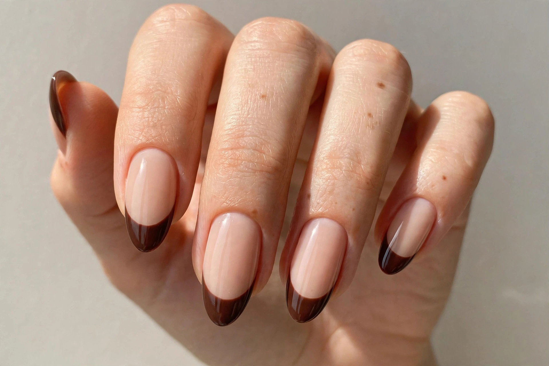 Rich chocolate brown french tips on nude almond nails