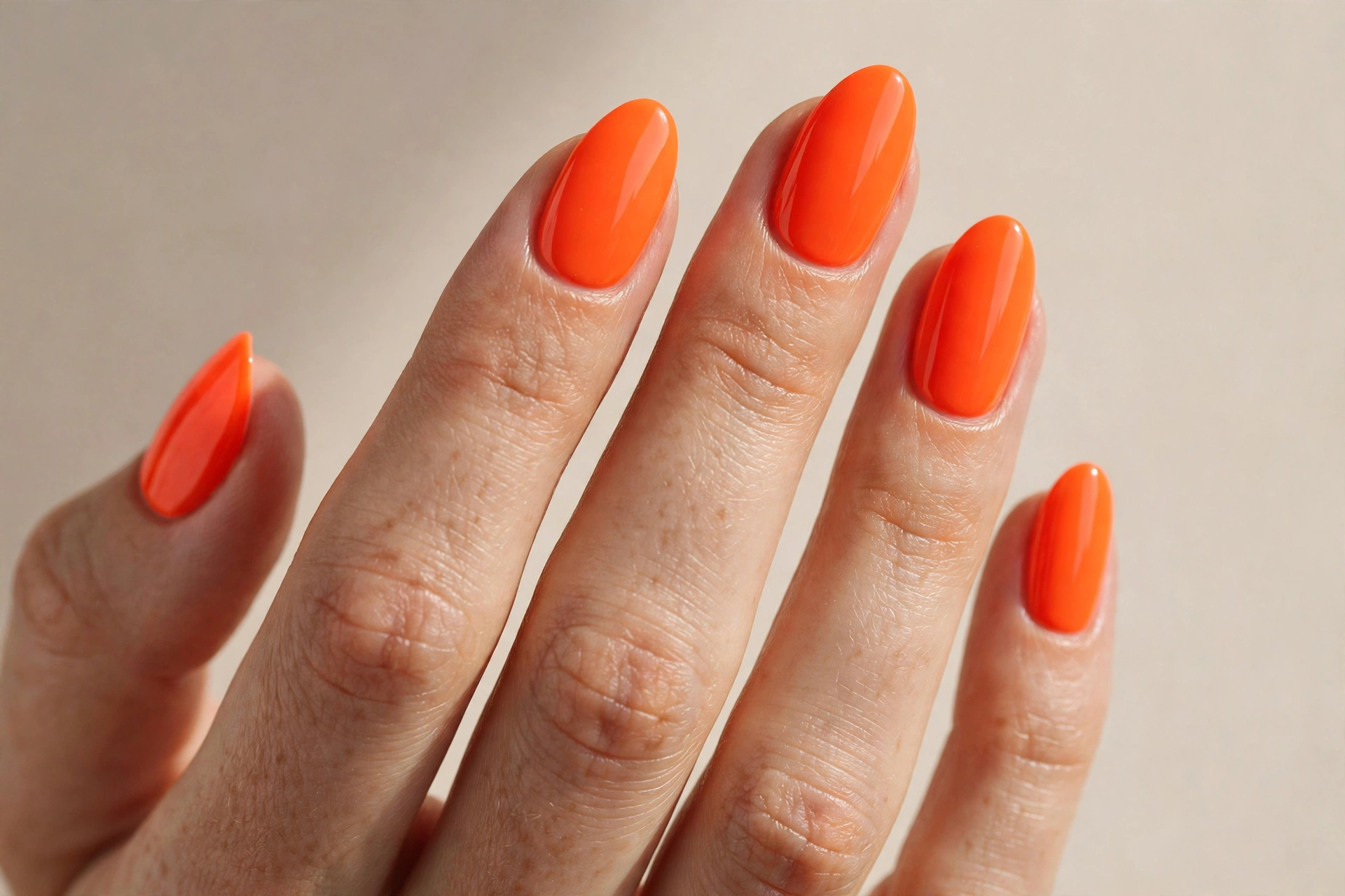 Bright neon orange manicure on almond nails
