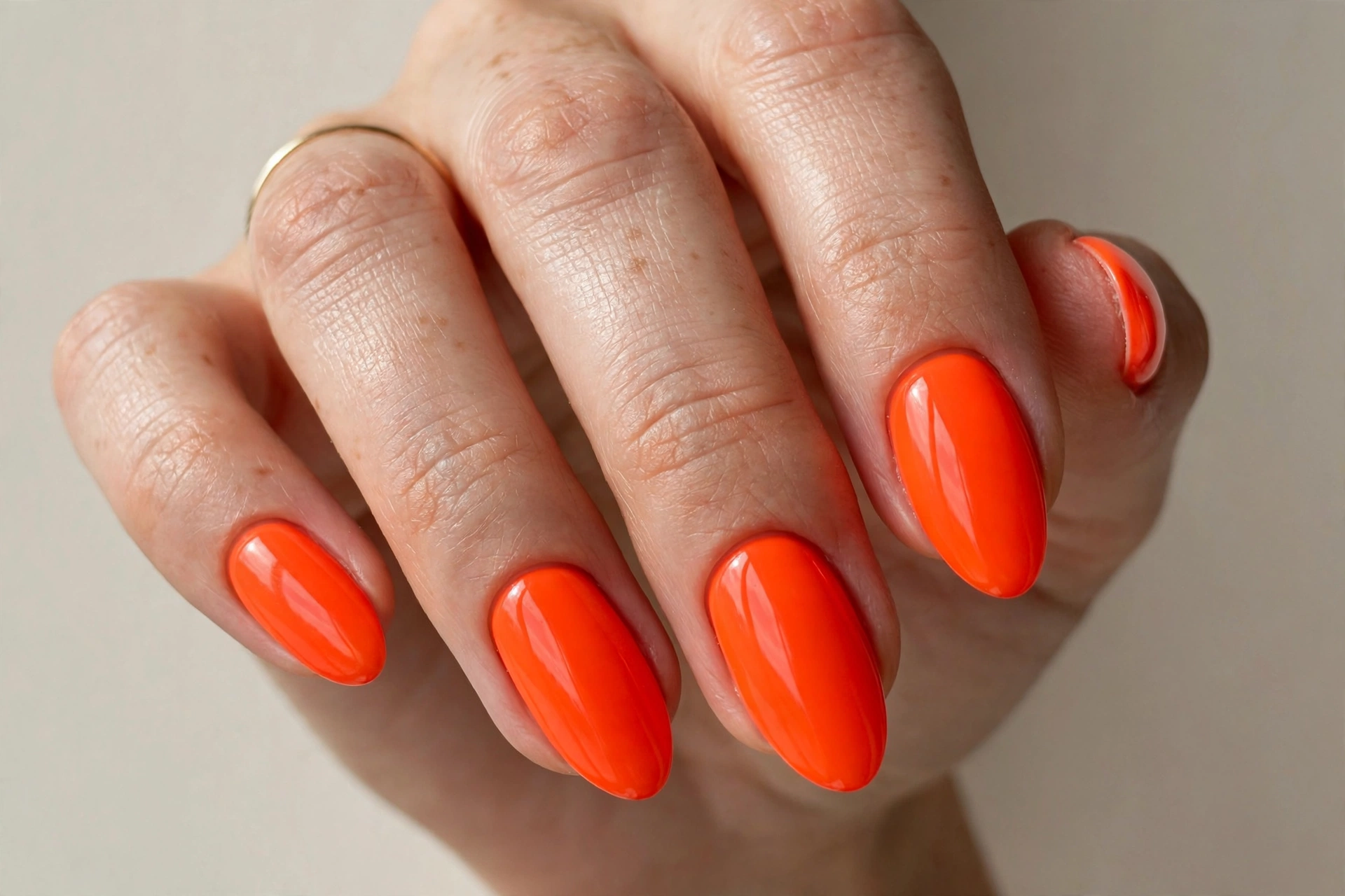 Bright neon orange manicure with an electric glowing finish