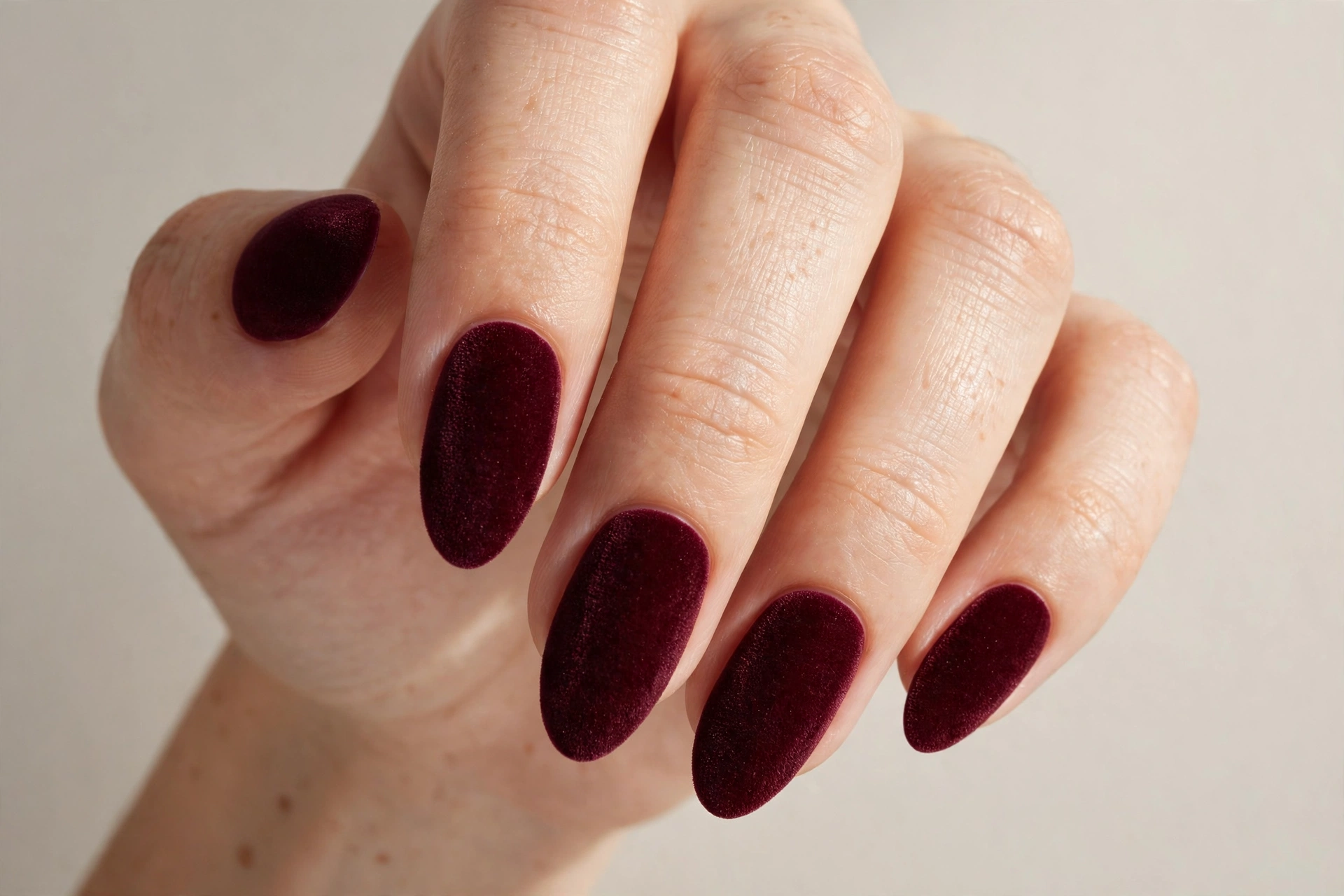 Close-up of deep burgundy manicure on oval shaped nails