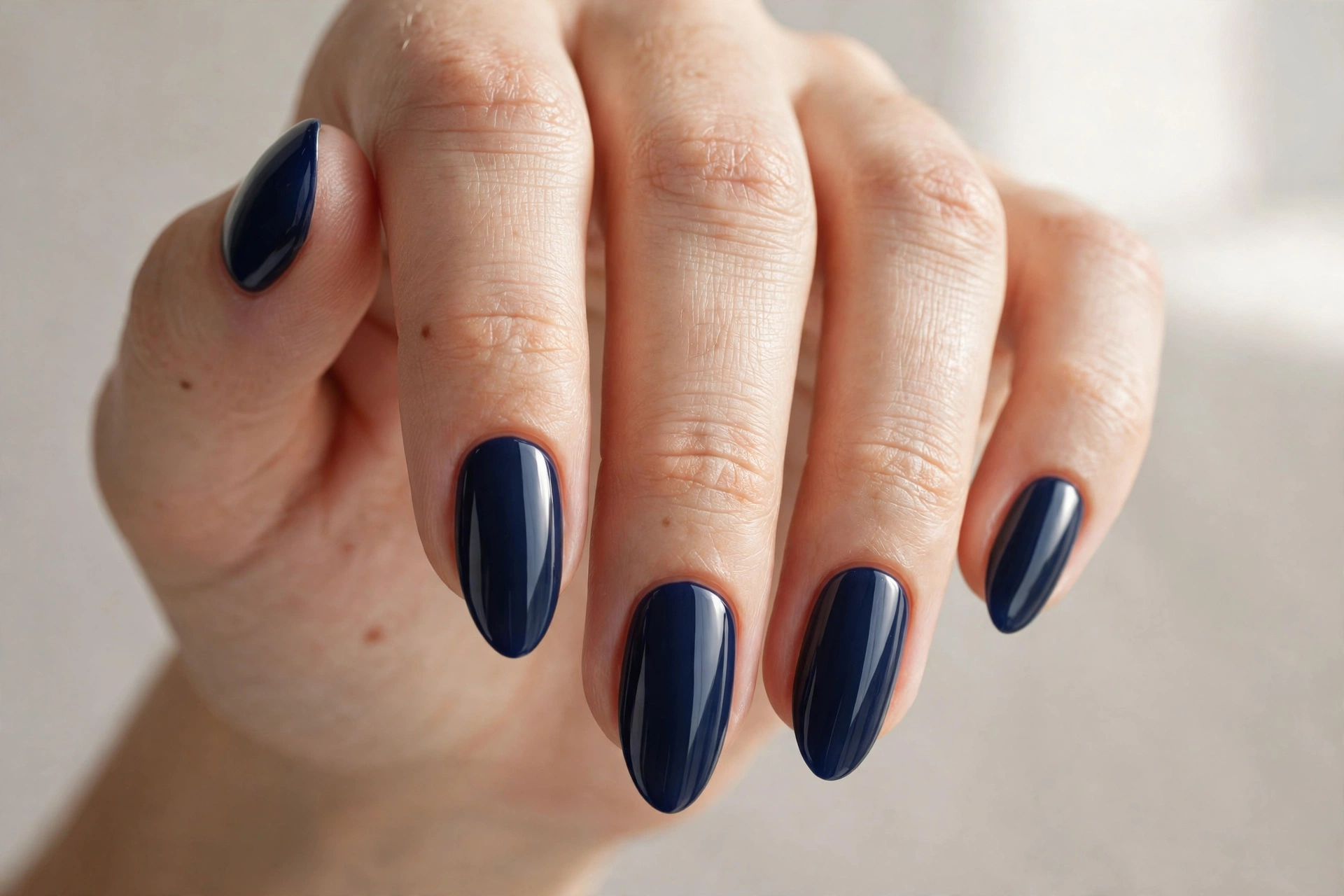 Close-up of deep navy blue manicure on oval shaped nails
