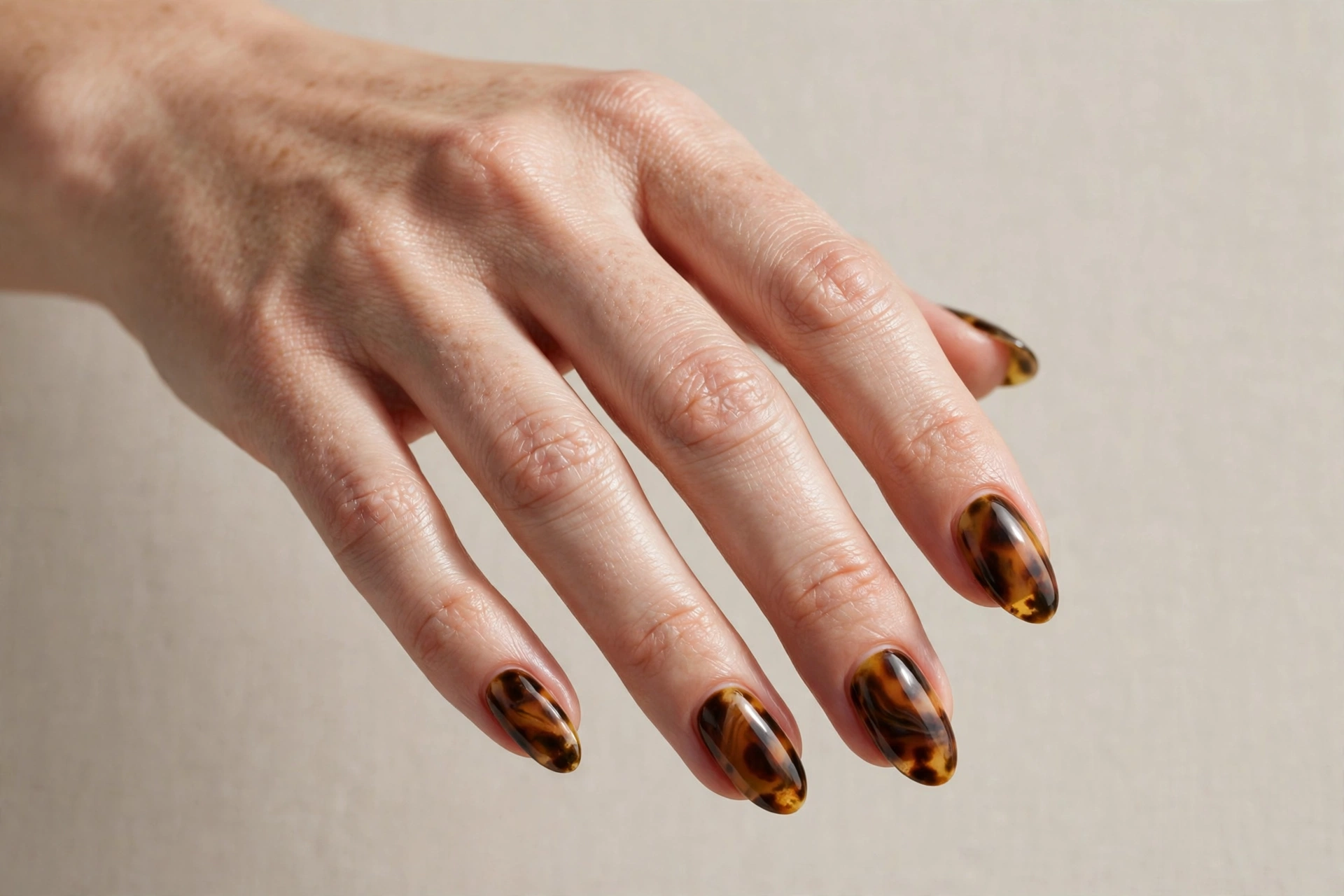 Close-up of tortoiseshell amber and brown swirl manicure on oval shaped nails
