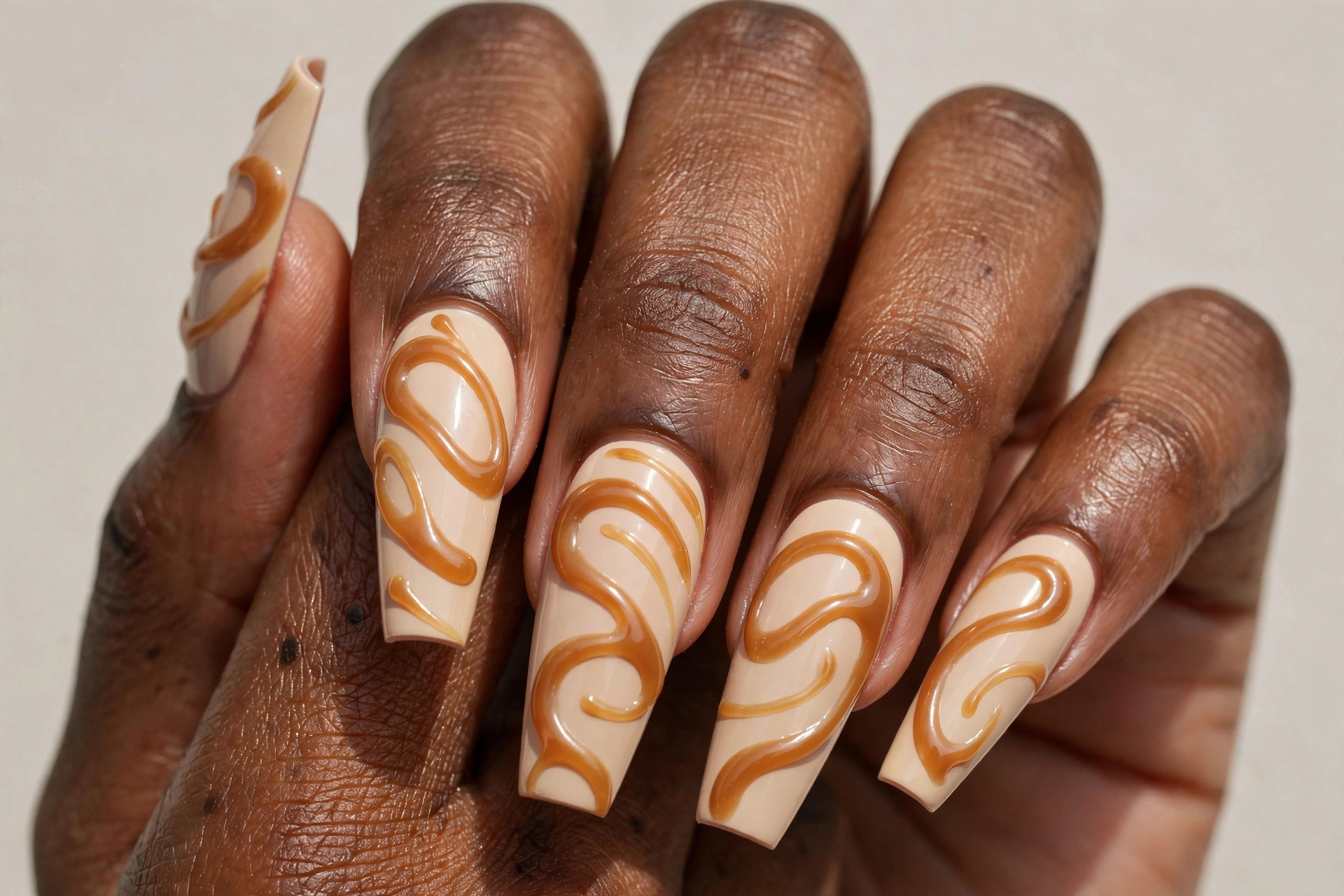Caramel drizzle latte nails with glossy caramel swirls on creamy beige base