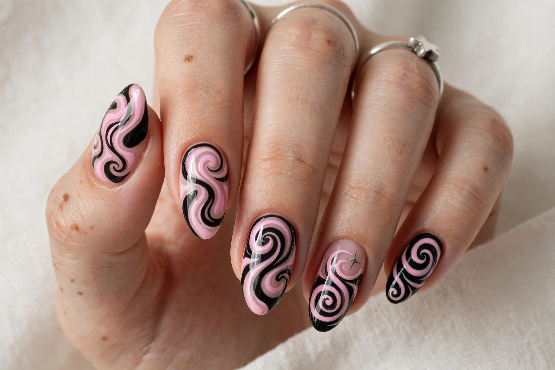 Almond nails with retro pink and black Y2K swirl nail art