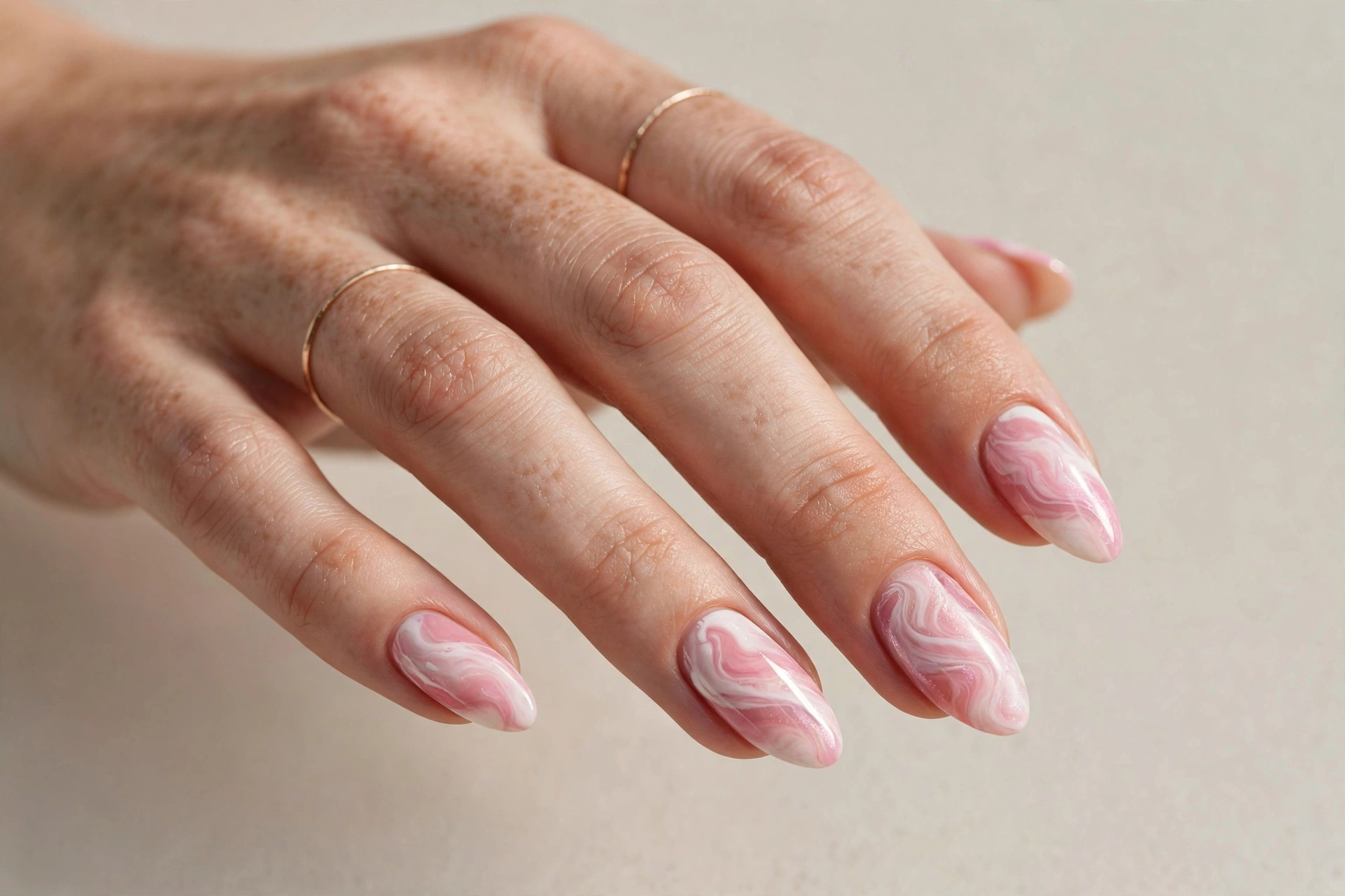 Close-up of a pink and white marble swirl nail design