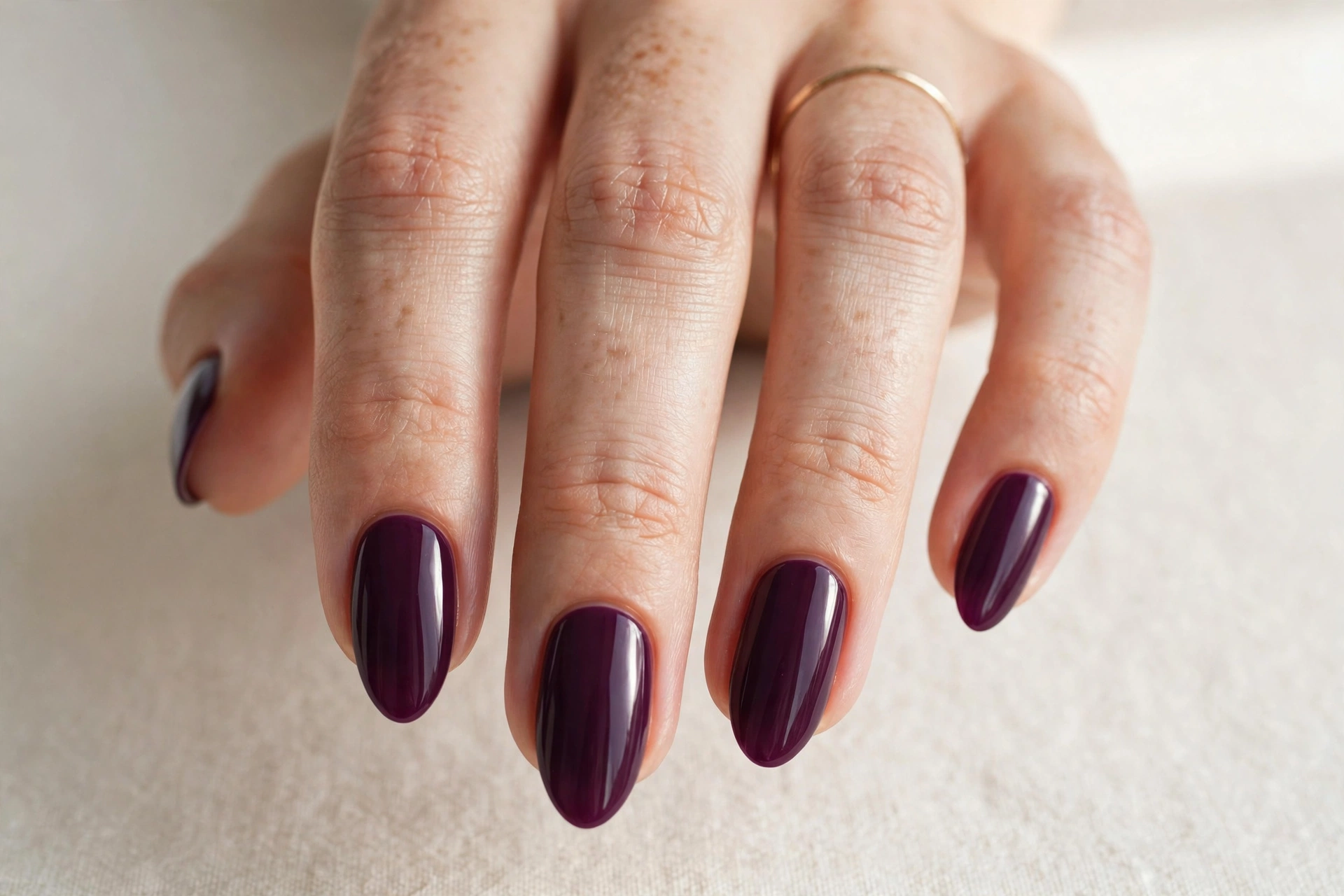 Classic deep plum purple solid manicure with glossy finish on almond nails