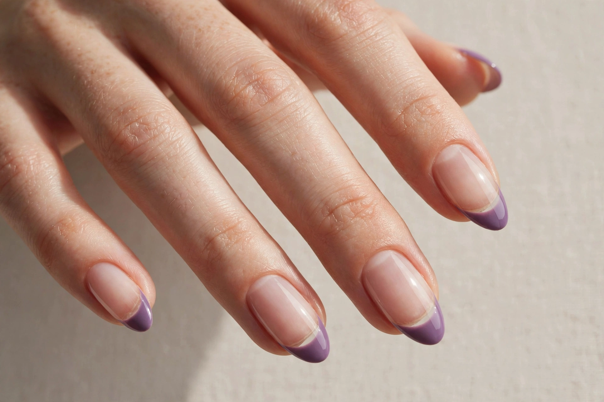 Negative space manicure with plum purple tips on clear natural nail base