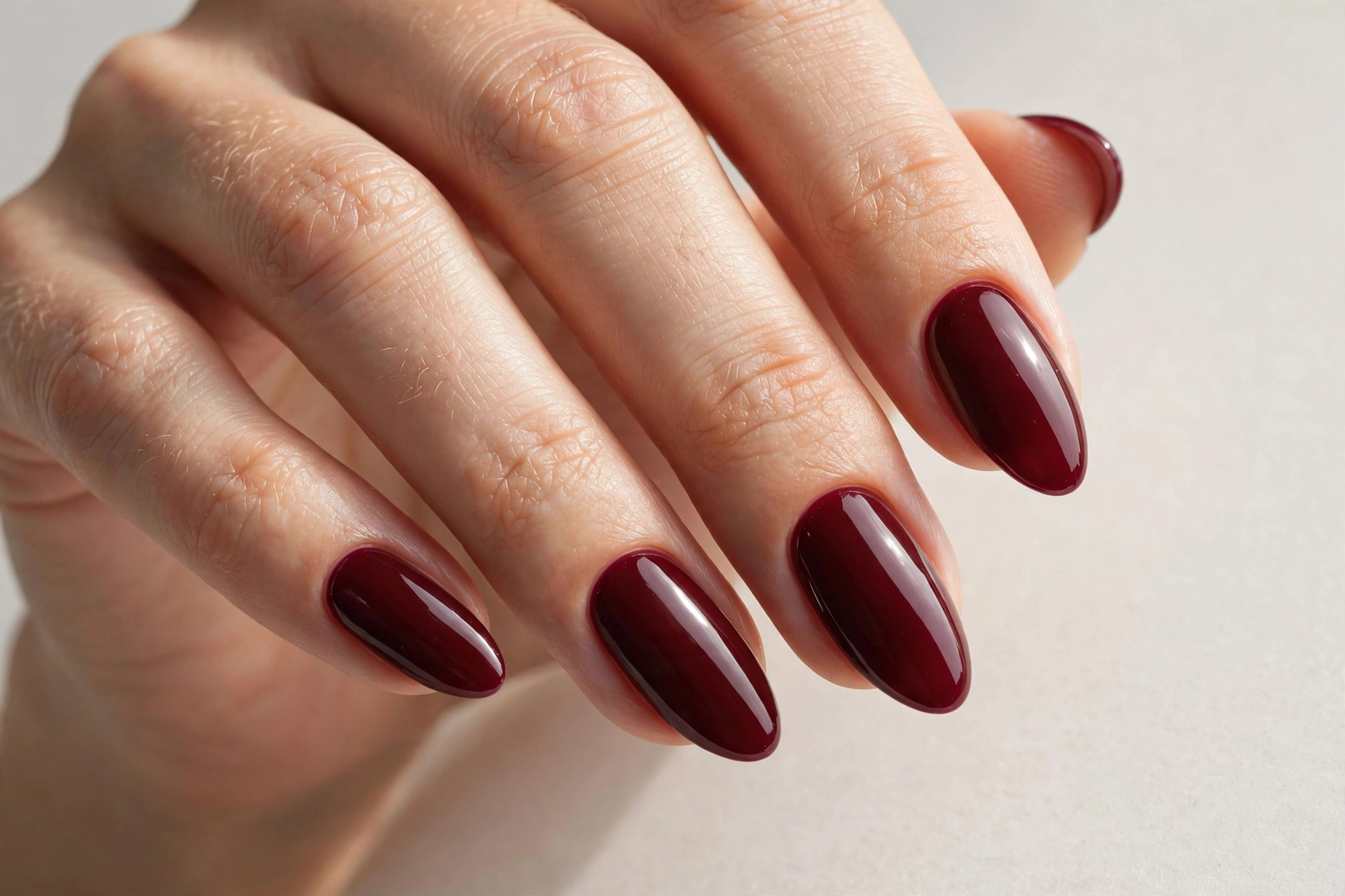 Glossy burgundy manicure on almond-shaped nails