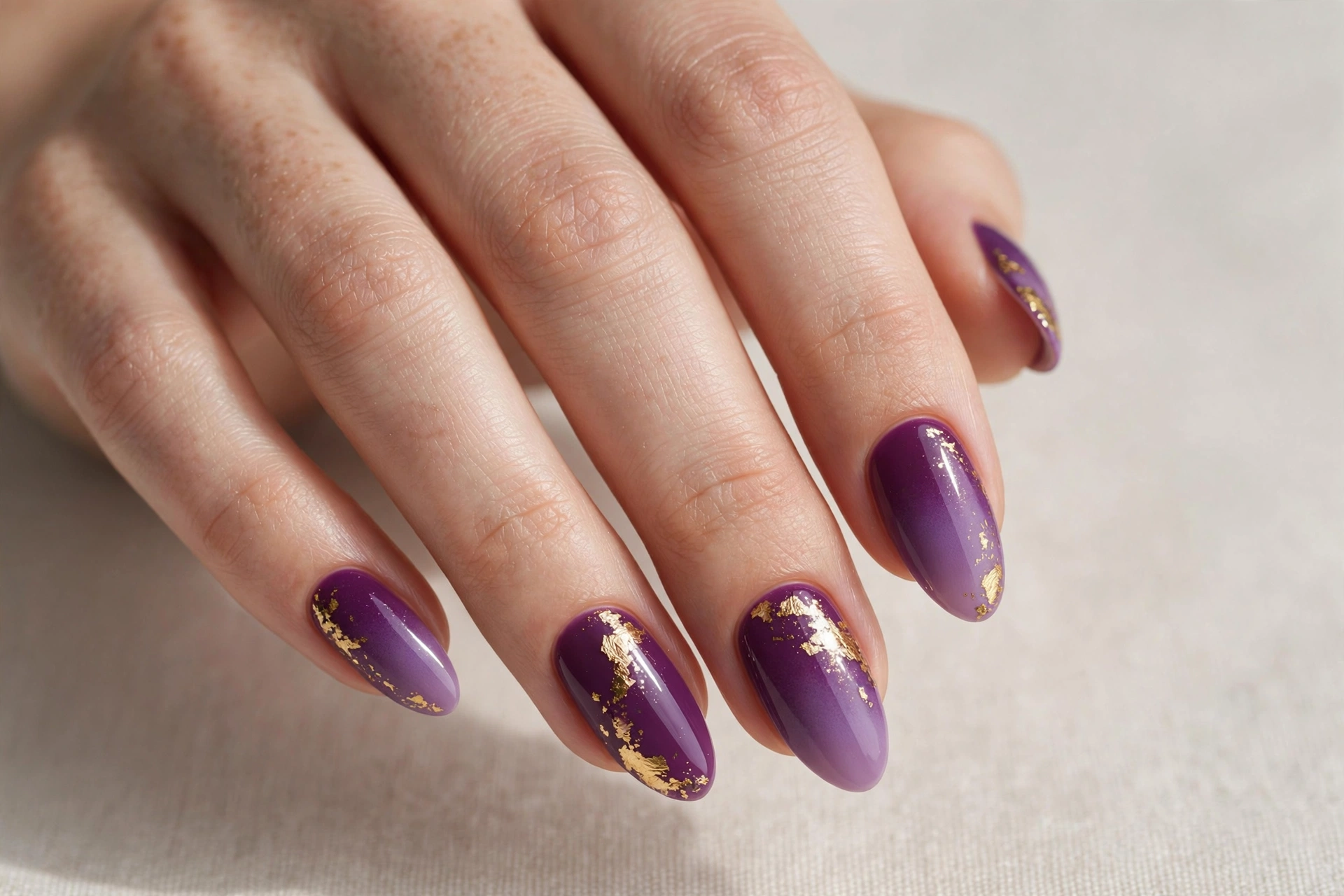 Plum purple ombre manicure with gold foil accents on almond nails