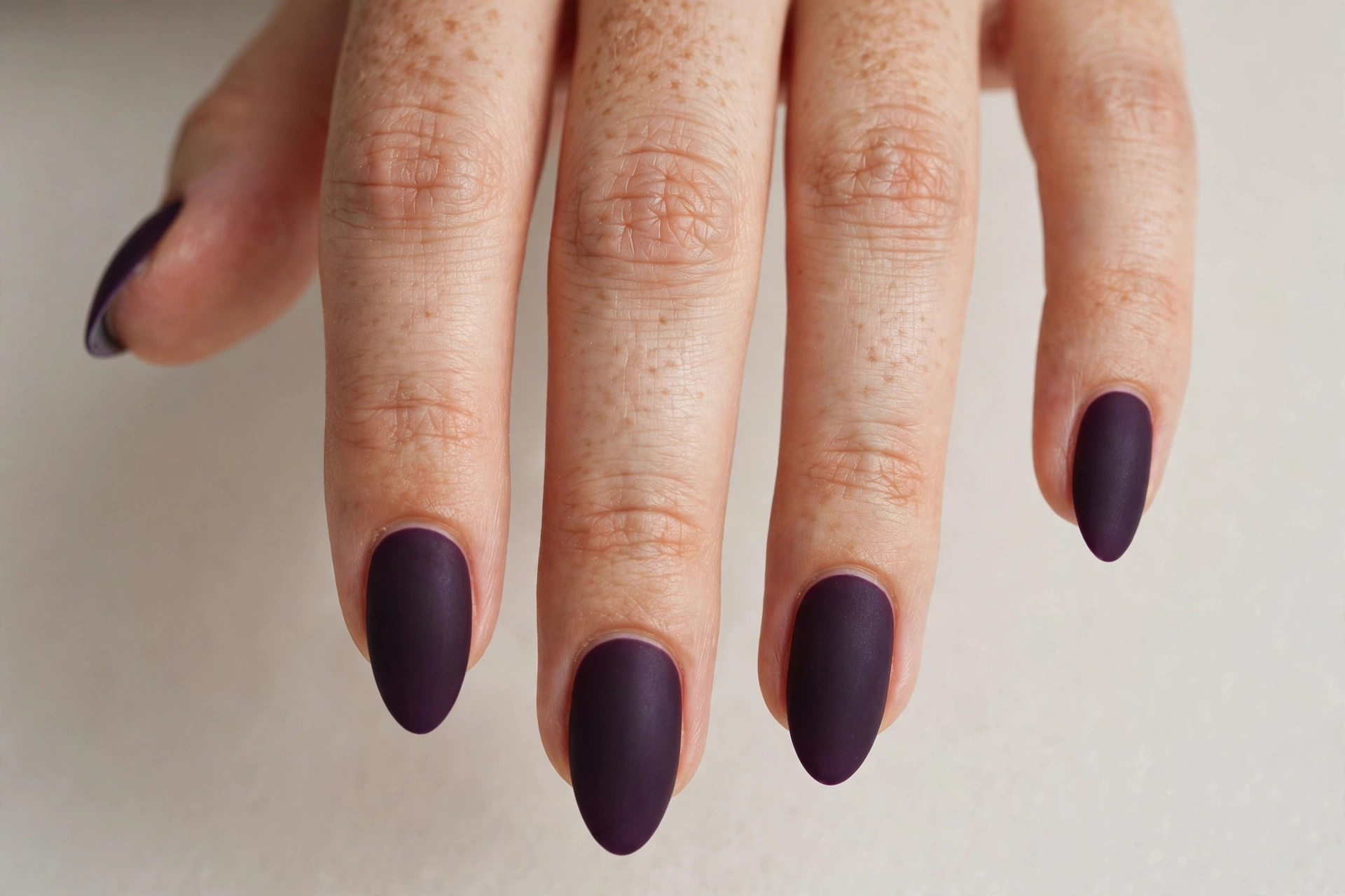 Matte eggplant dark purple manicure on almond-shaped nails