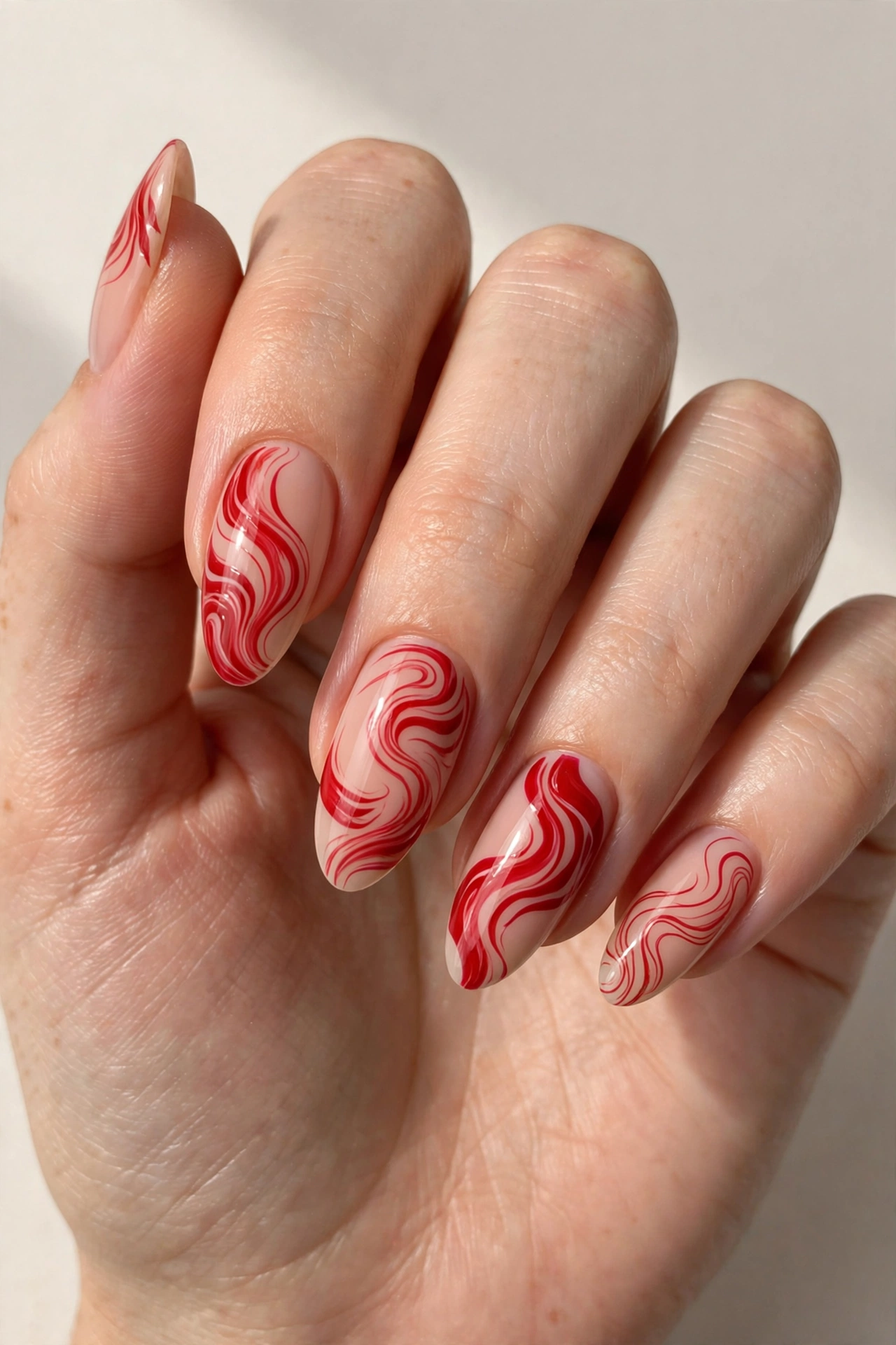 Red abstract swirl nail art on nude base