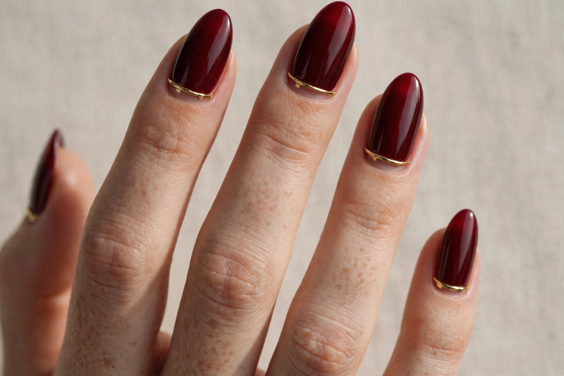 Dark red manicure with gold cuticle cuff detail