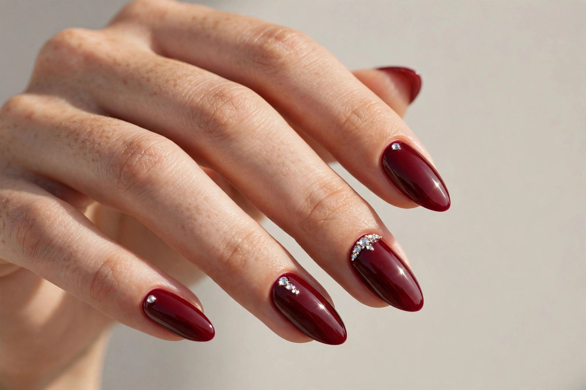 Dark cherry red manicure with rhinestone accents