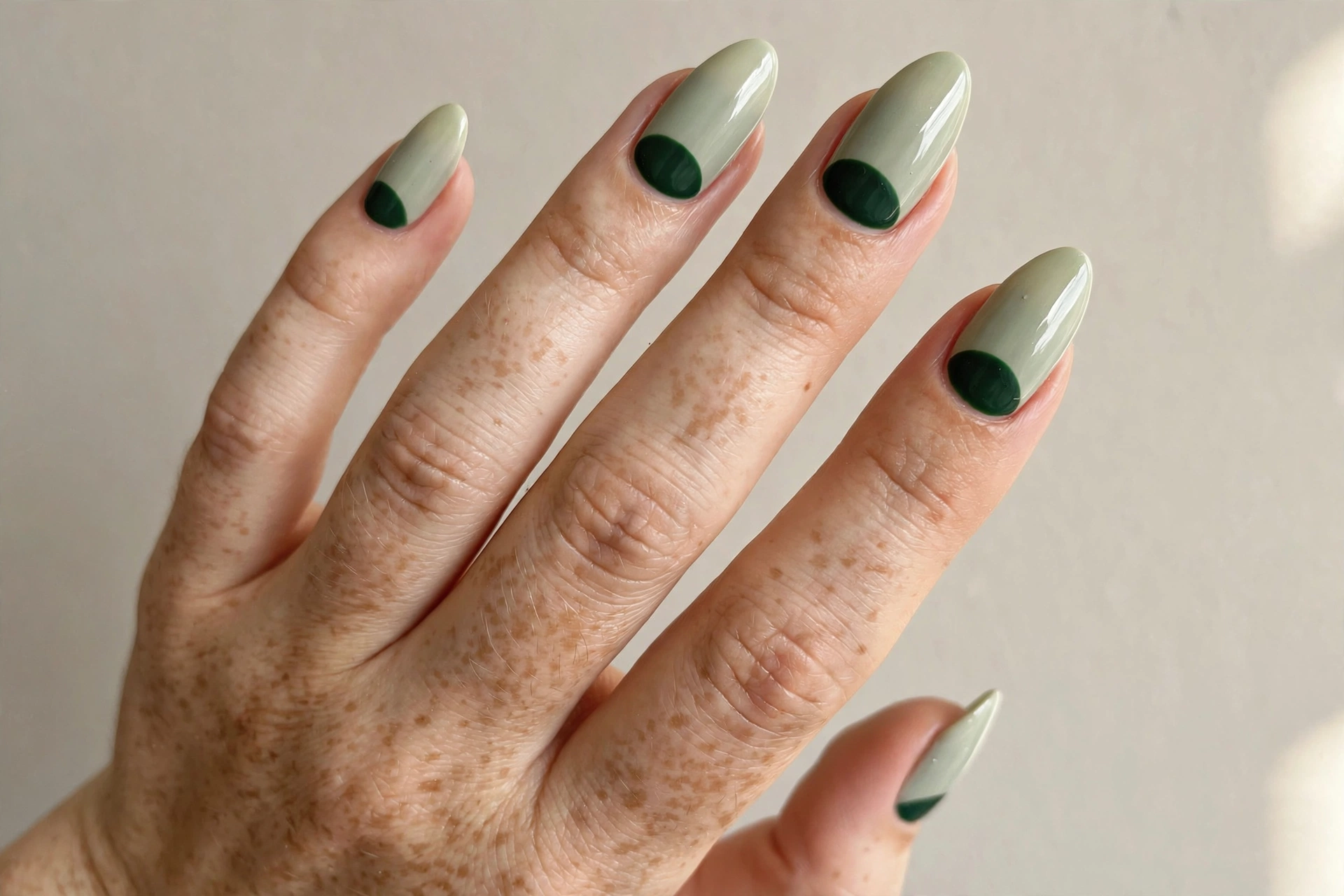 Sage green half-moon manicure with deep green crescent at the cuticle