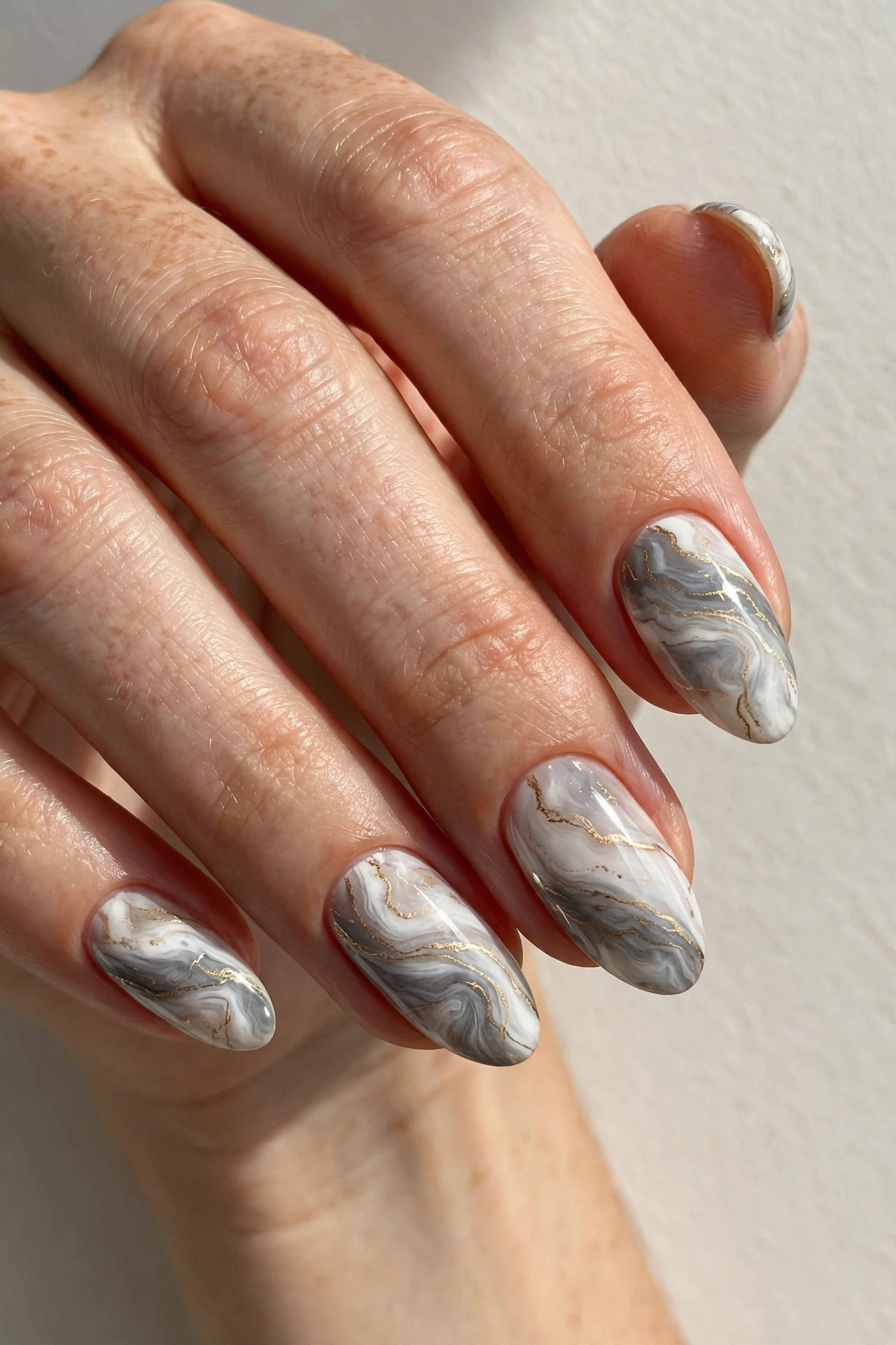 Marble swirl nail art in white and grey with fine gold veining