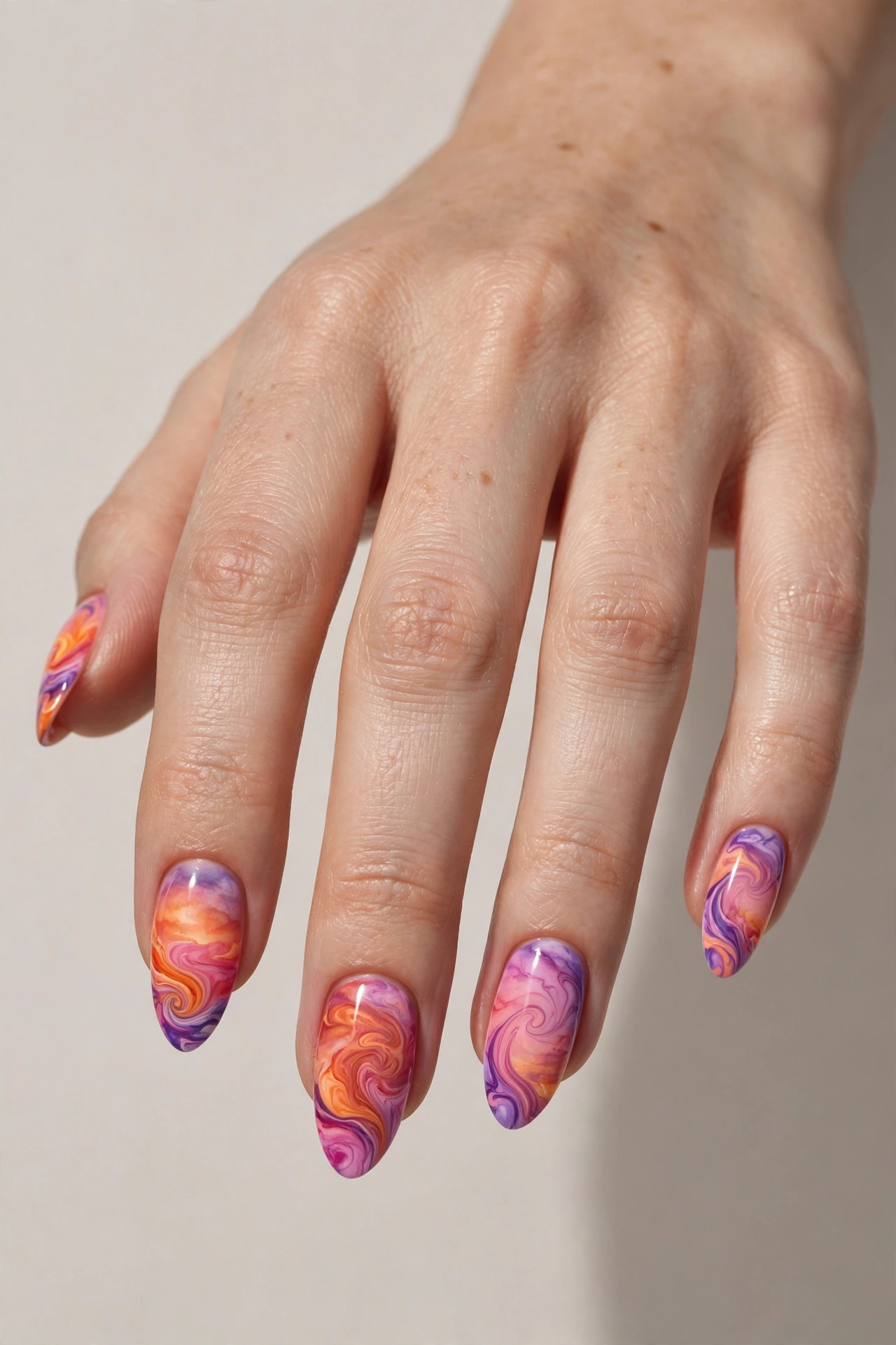 Sunset swirl nail art with orange, pink and purple gradient swirls