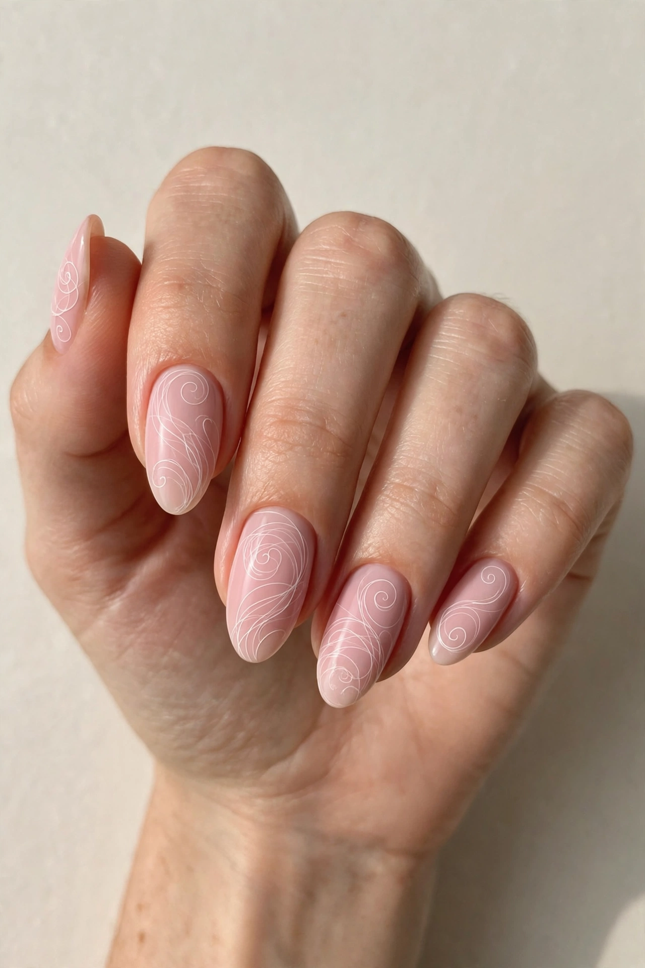 Delicate fine white line swirls on soft pastel pink nail base