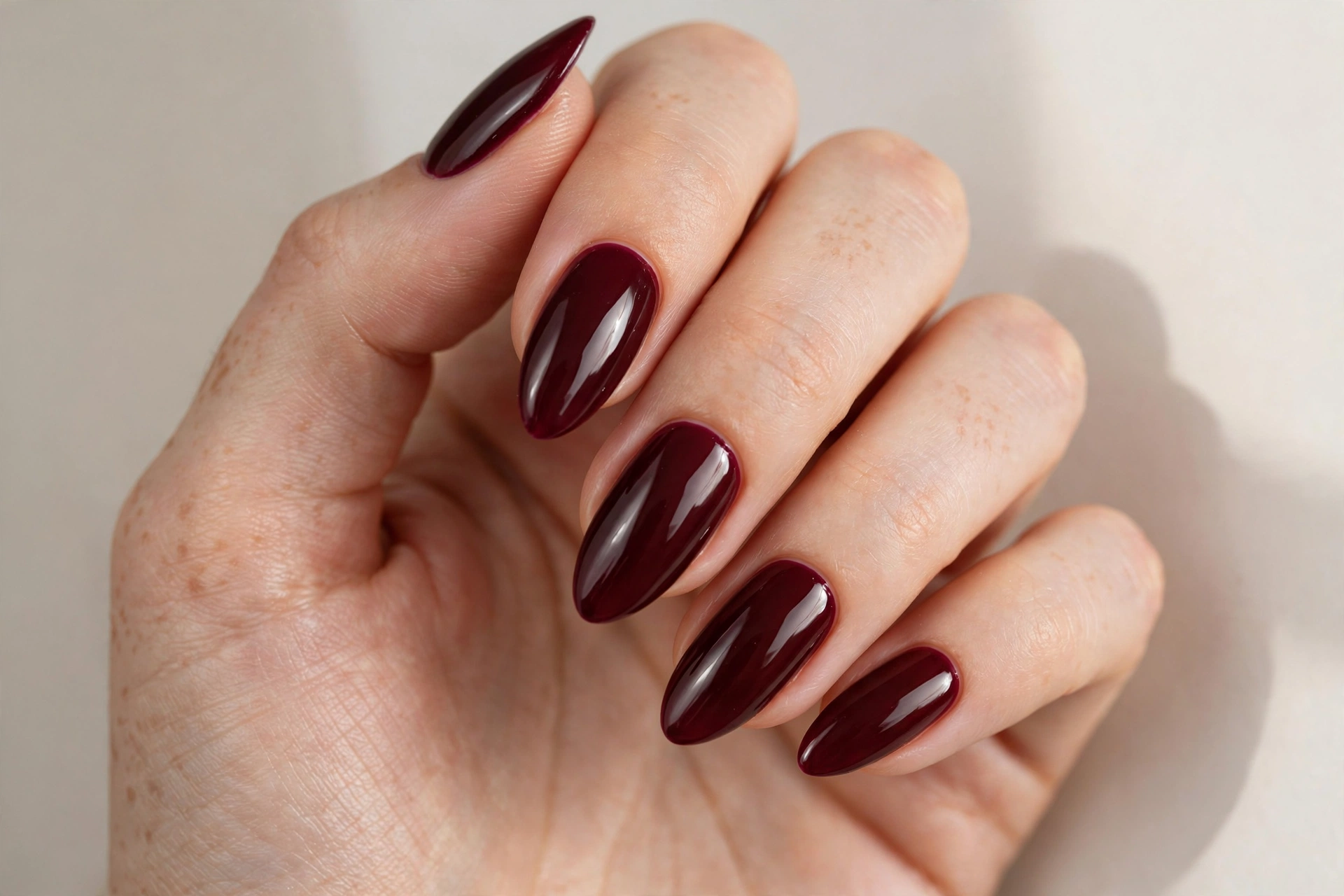 Deep burgundy wine-colored glossy manicure on almond nails
