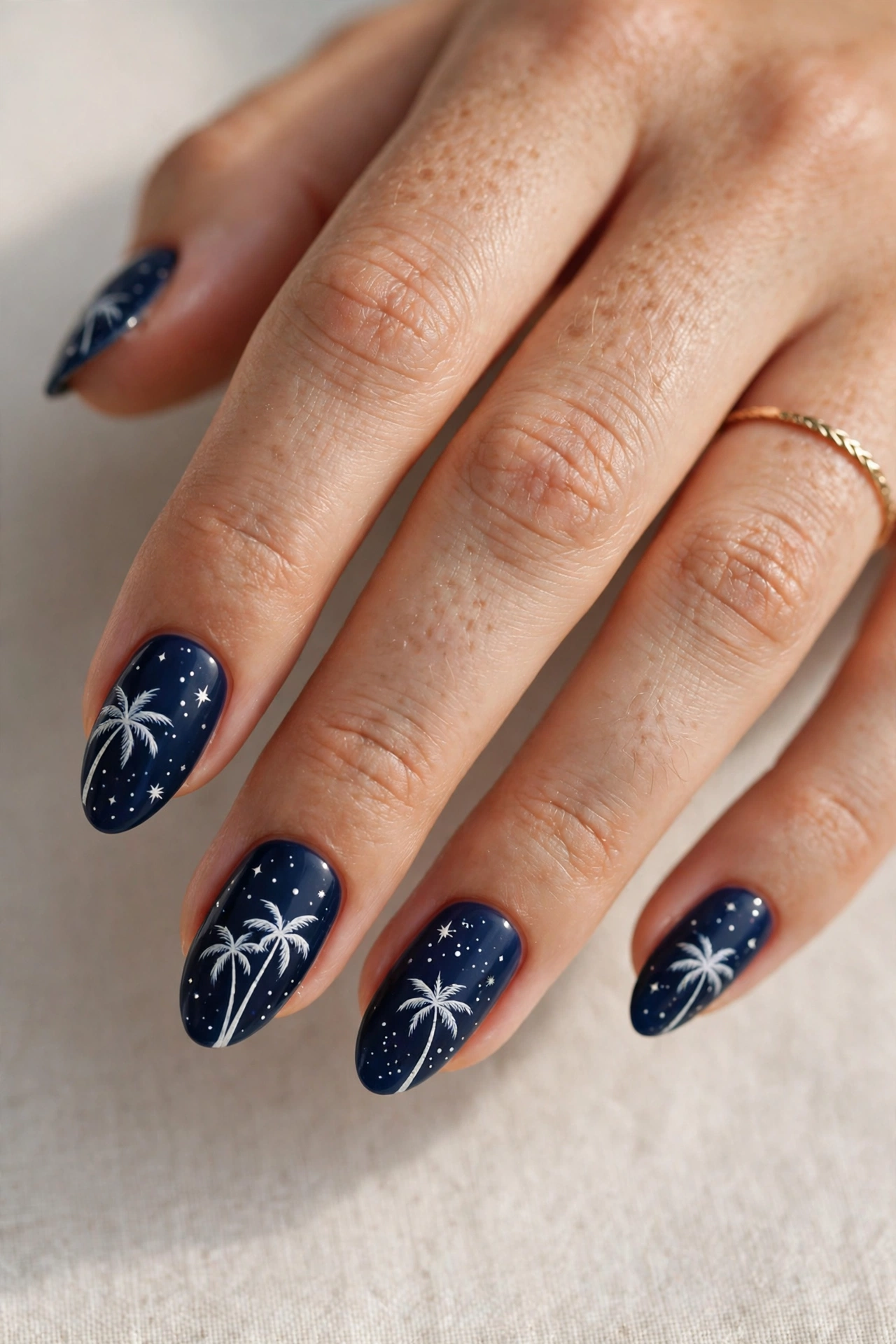 Island night manicure with deep navy blue, white palm silhouettes and tiny stars