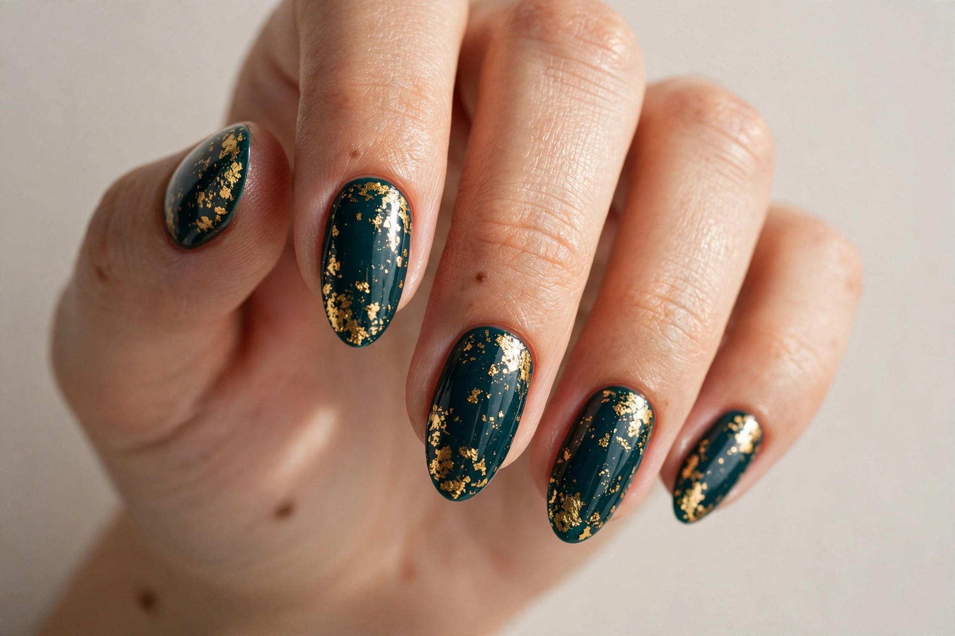 Dark teal nails with gold foil flakes
